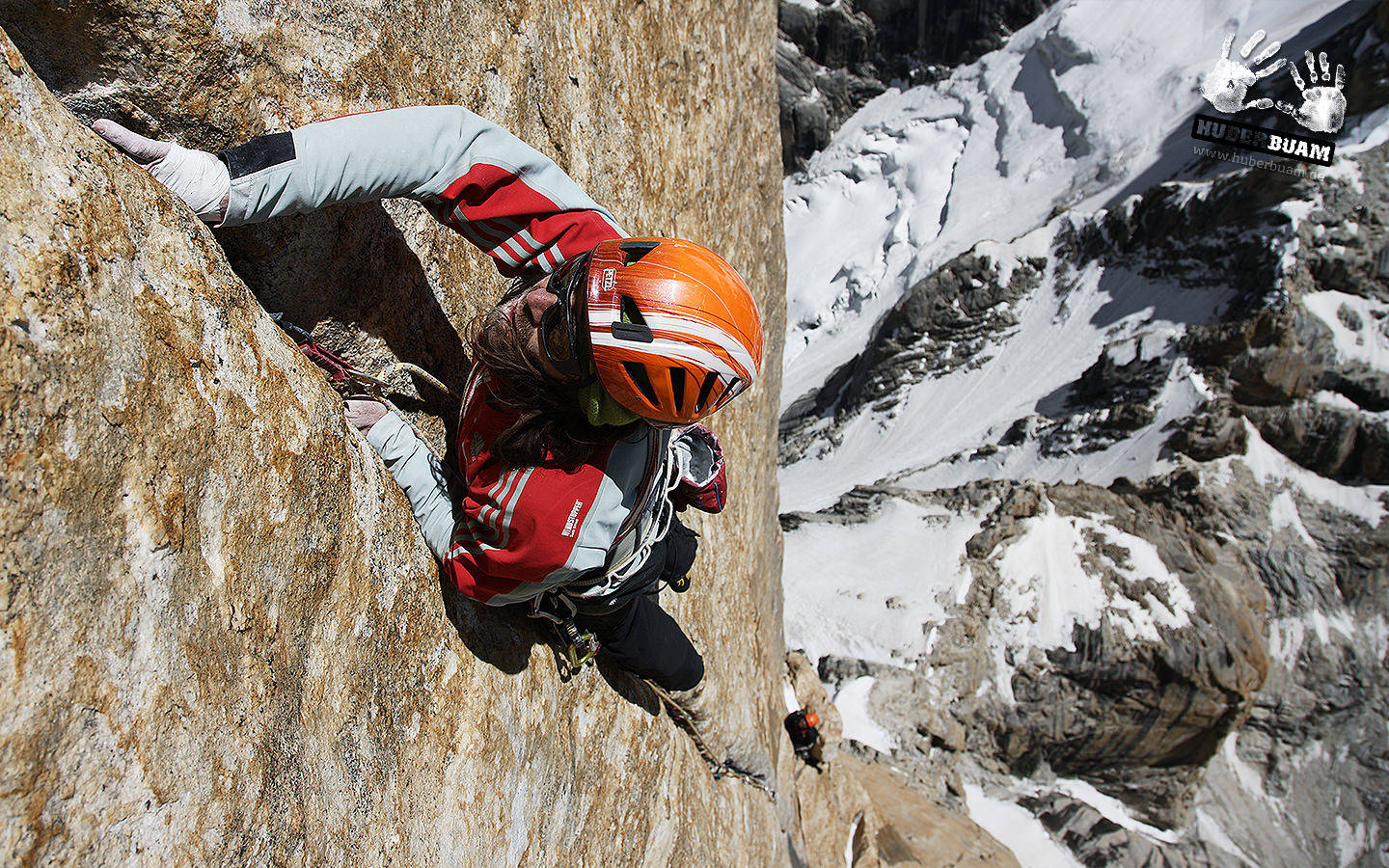 Climbing 桌布 壁紙 — 一名身穿紅色裝備的攀岩者正在攀登陽光照耀的岩壁，遠方有積雪的山峰和下方另一位攀岩者。