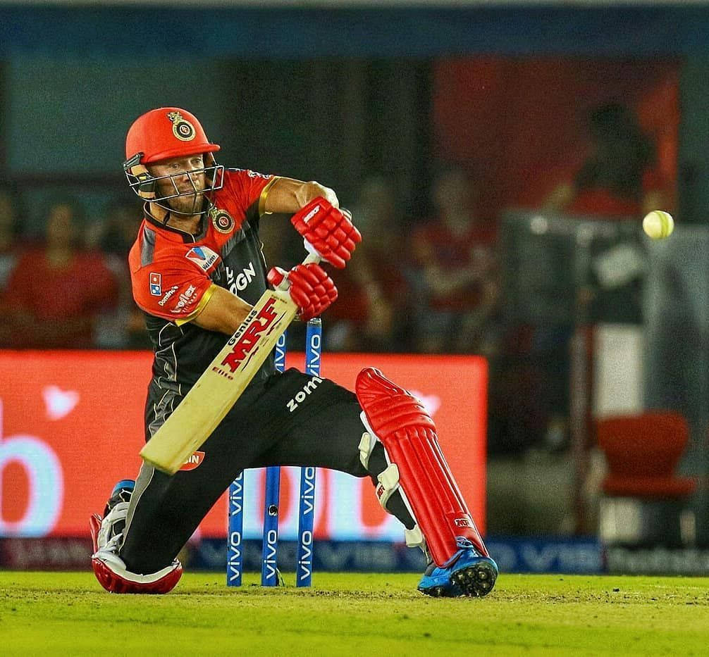 royal challengers bangalore 桌布 壁紙 — 一名身穿紅色裝備的板球擊球手在夜間比賽中，在體育場燈光下揮動球棒擊球。