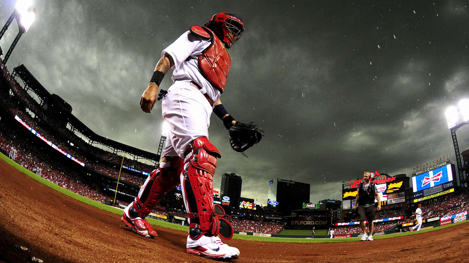 Yadier Molina 桌布 壁紙 — 一名身穿紅色裝備的棒球捕手在風雨交加的夜空下，從座無虛席的球場離場。