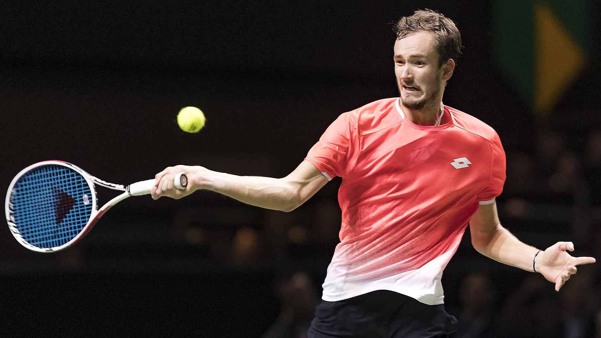 Tennis 桌布 壁紙 — 一名身穿紅色襯衫的男網球運動員在激烈的室內比賽中揮拍擊打黃球。