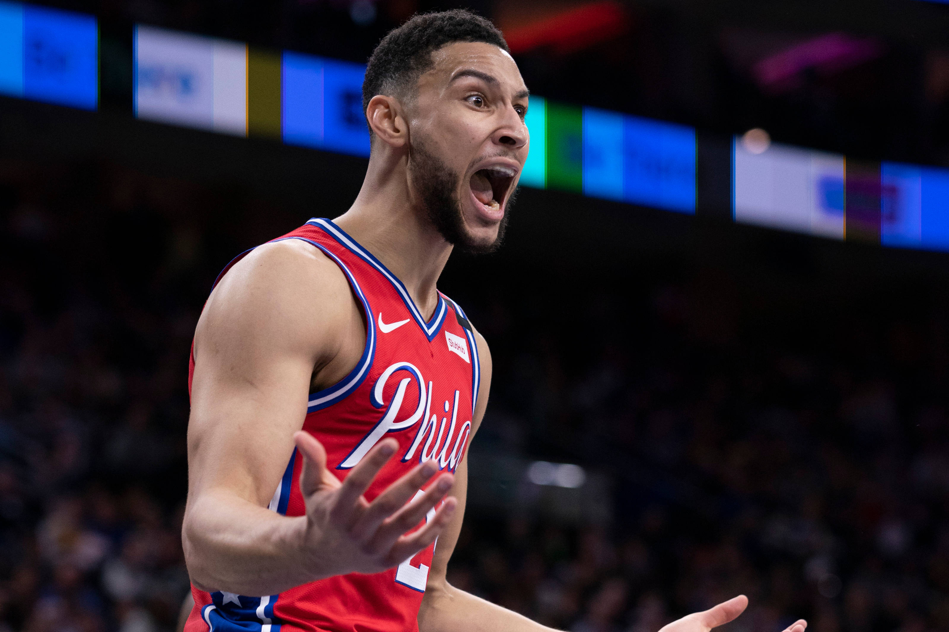 76ers 桌布 壁紙 — 一名身穿紅色費城球衣的籃球運動員在場館燈光下於比賽中激情吶喊。
