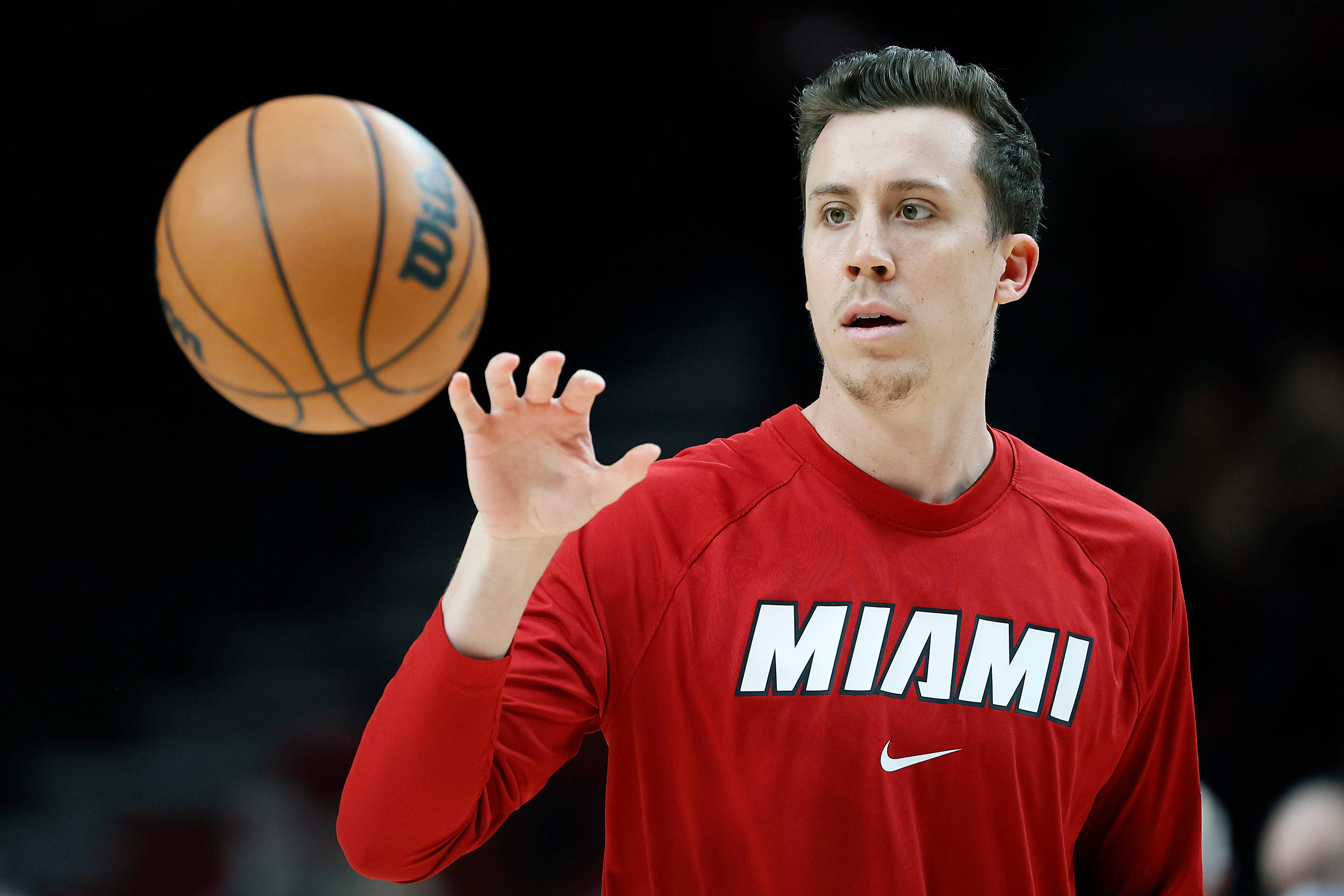 duncan robinson 桌布 壁紙 — 一名身穿紅色邁阿密球衣的籃球運動員在深色背景下將籃球拋向空中。