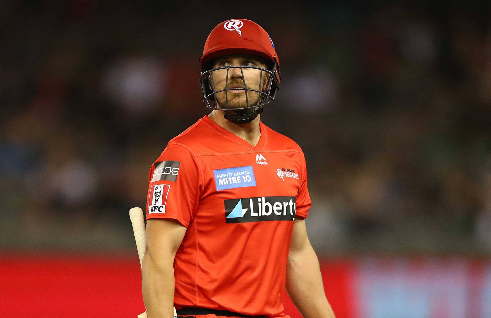 Aaron Finch 桌布 壁紙 — 一名身穿紅色頭盔和球衣的板球擊球手在體育場燈光下的夜間比賽中專注地站立。