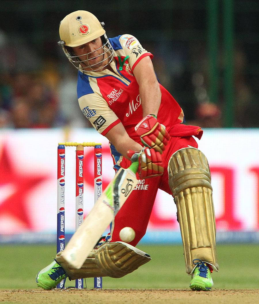 royal challengers bangalore 桌布 壁紙 — 一名身穿紅藍球衣的板球擊球手在夜間比賽中，在球場燈光下揮動球棒擊球。