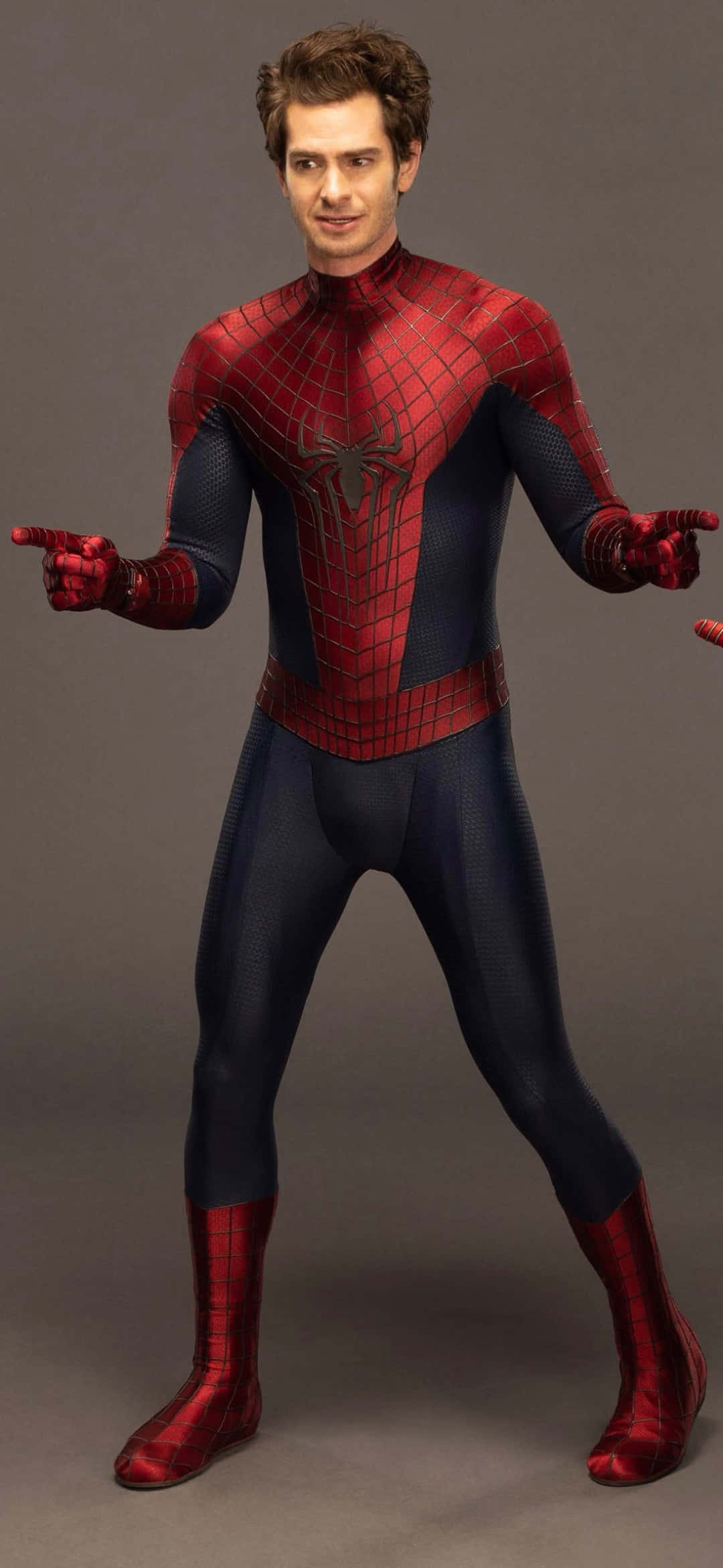 Andrew Garfield Spider Man 桌布 壁紙 — 一名身穿紅藍蜘蛛主題超級英雄戰衣的男子，在純灰色工作室背景前自信地擺姿勢。