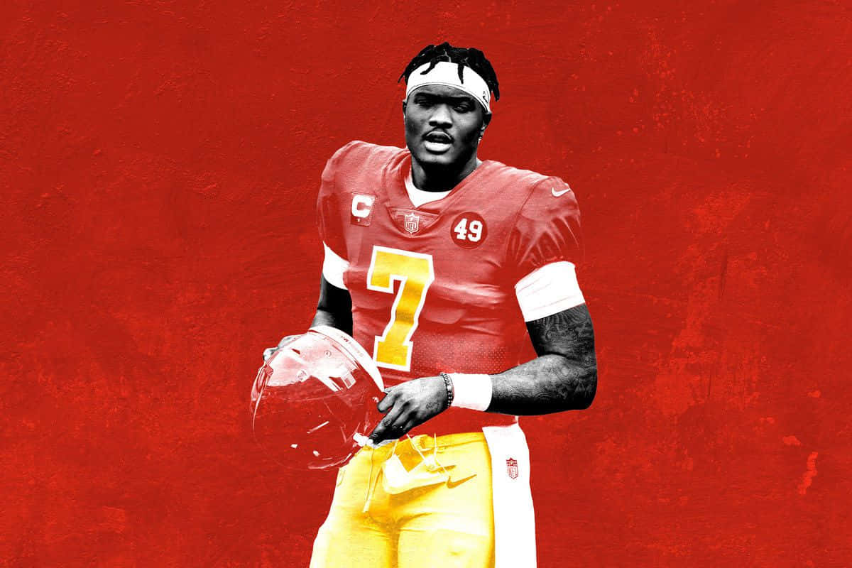 Dwayne Haskins 桌布 壁紙 — 一名身穿紅金球衣的美式足球員在紋理紅背景前手持頭盔。