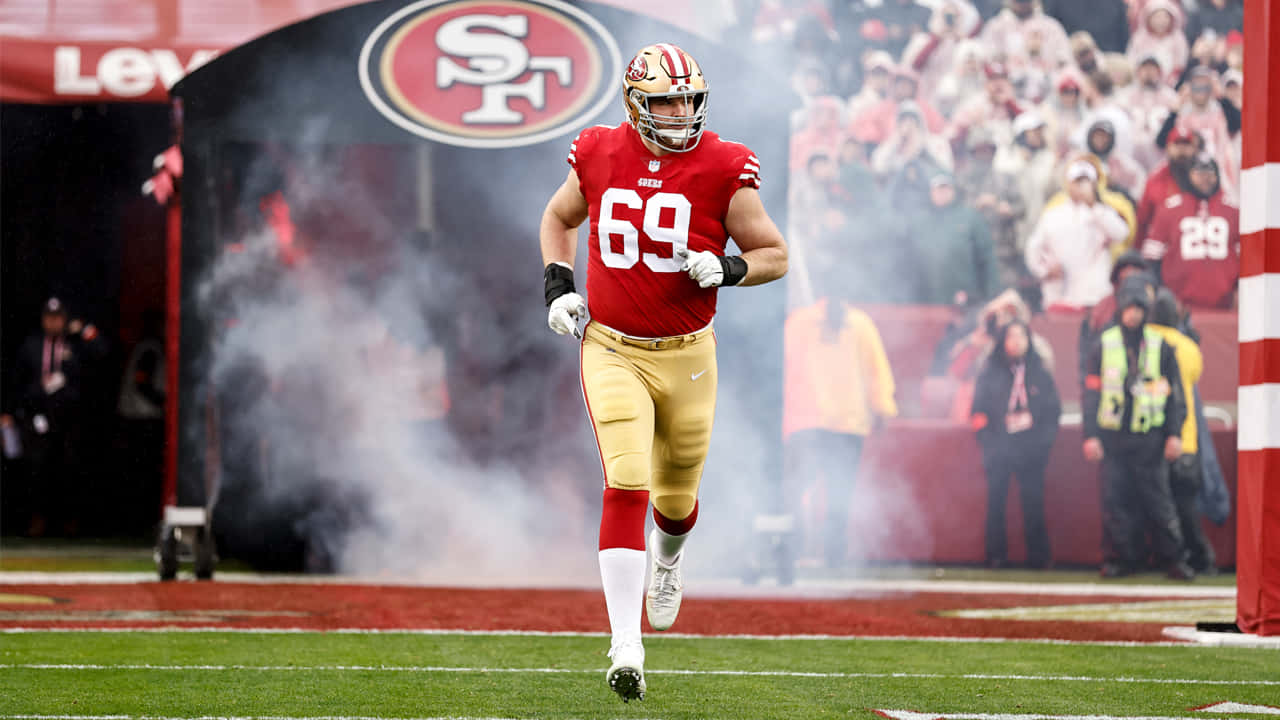Mike Mcglinchey 桌布 壁紙 — 一名身穿紅金色球衣的舊金山四九人美式足球員在李維斯球場穿過煙霧跑入球場。