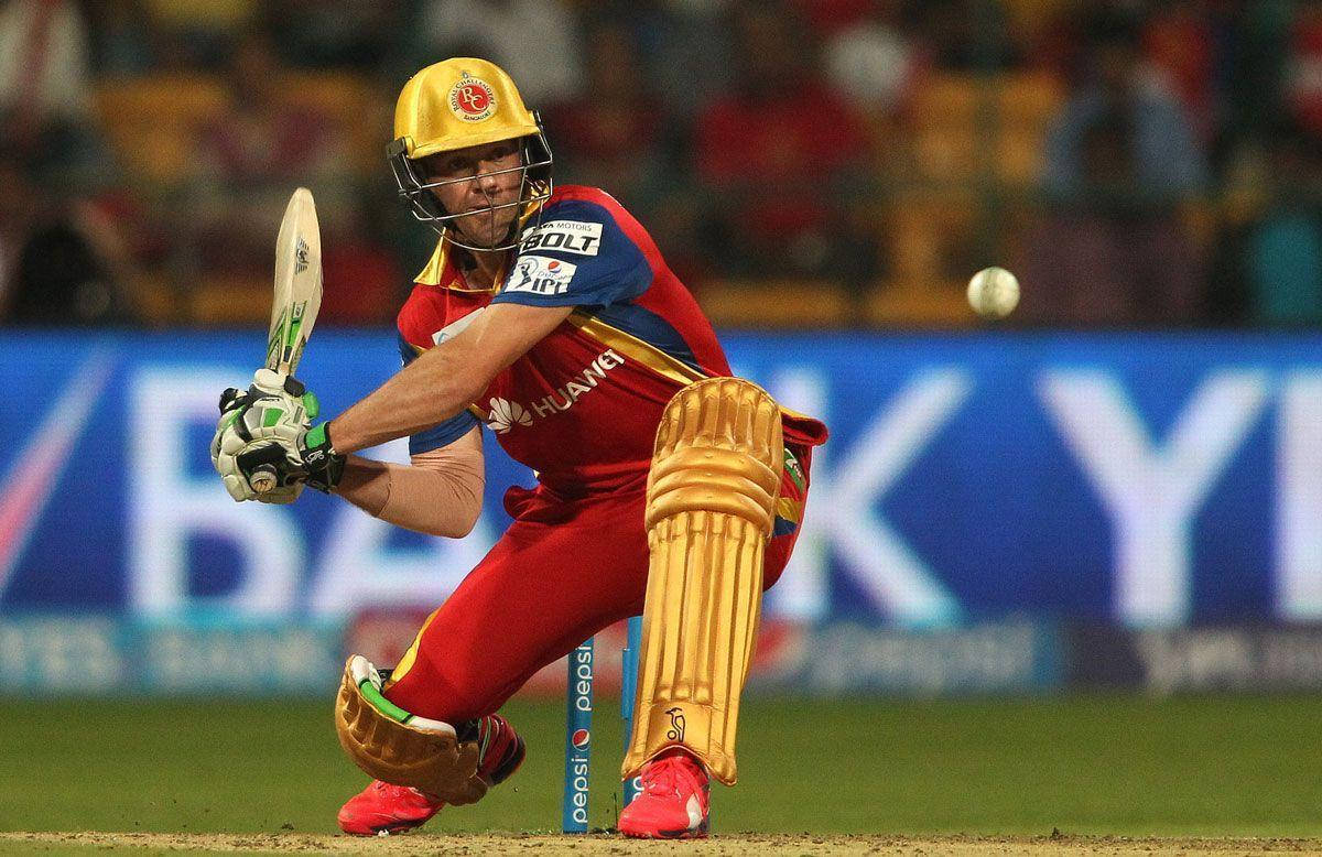 royal challengers bangalore 桌布 壁紙 — 一名身穿紅金裝備的板球擊球手在夜間比賽中，於球場燈光下揮棒擊球。