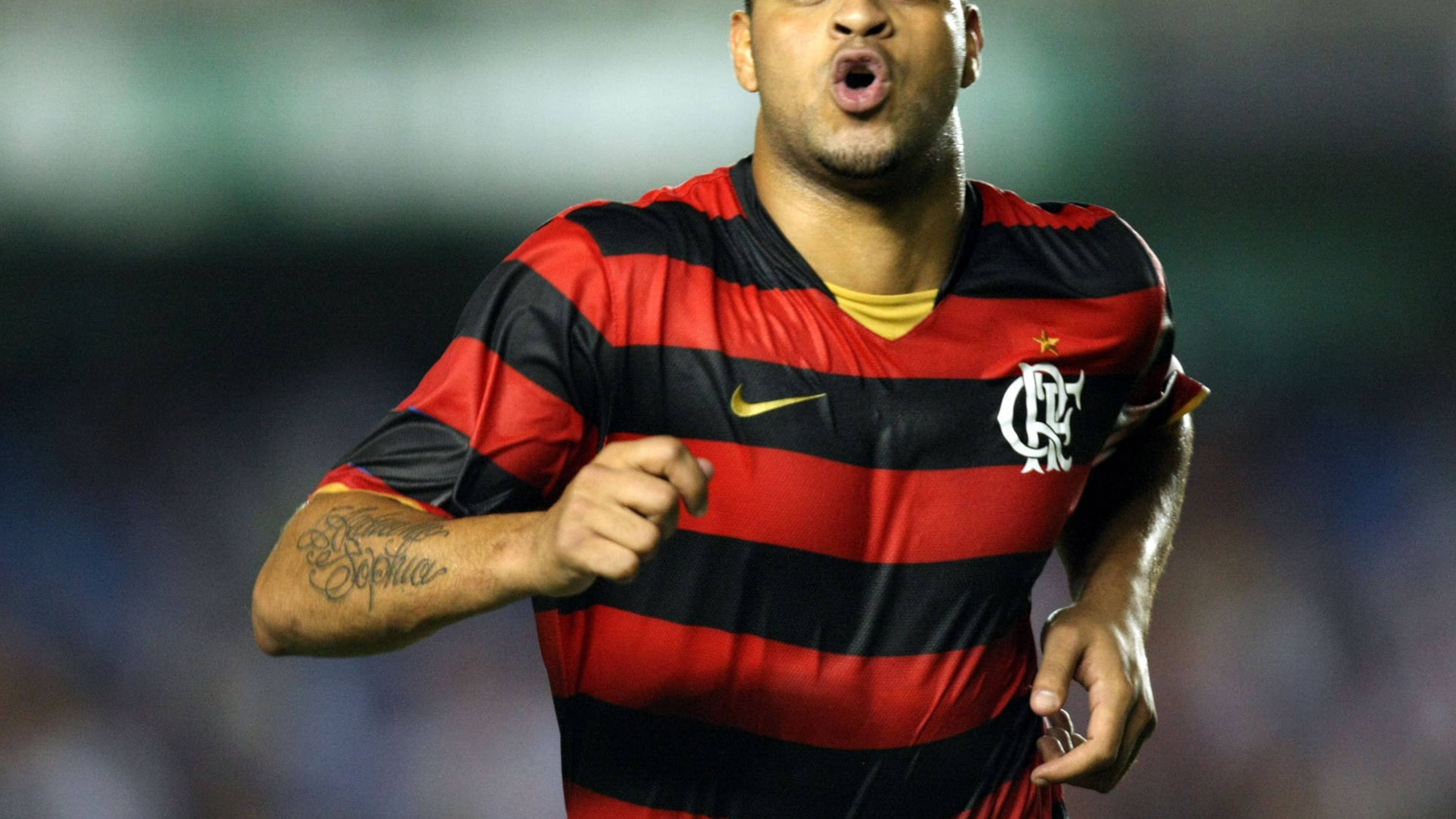 flamengo fc 桌布 壁紙 — 一名身穿紅黑條紋球衣的足球員在球場燈光下握緊拳頭張開嘴巴慶祝。
