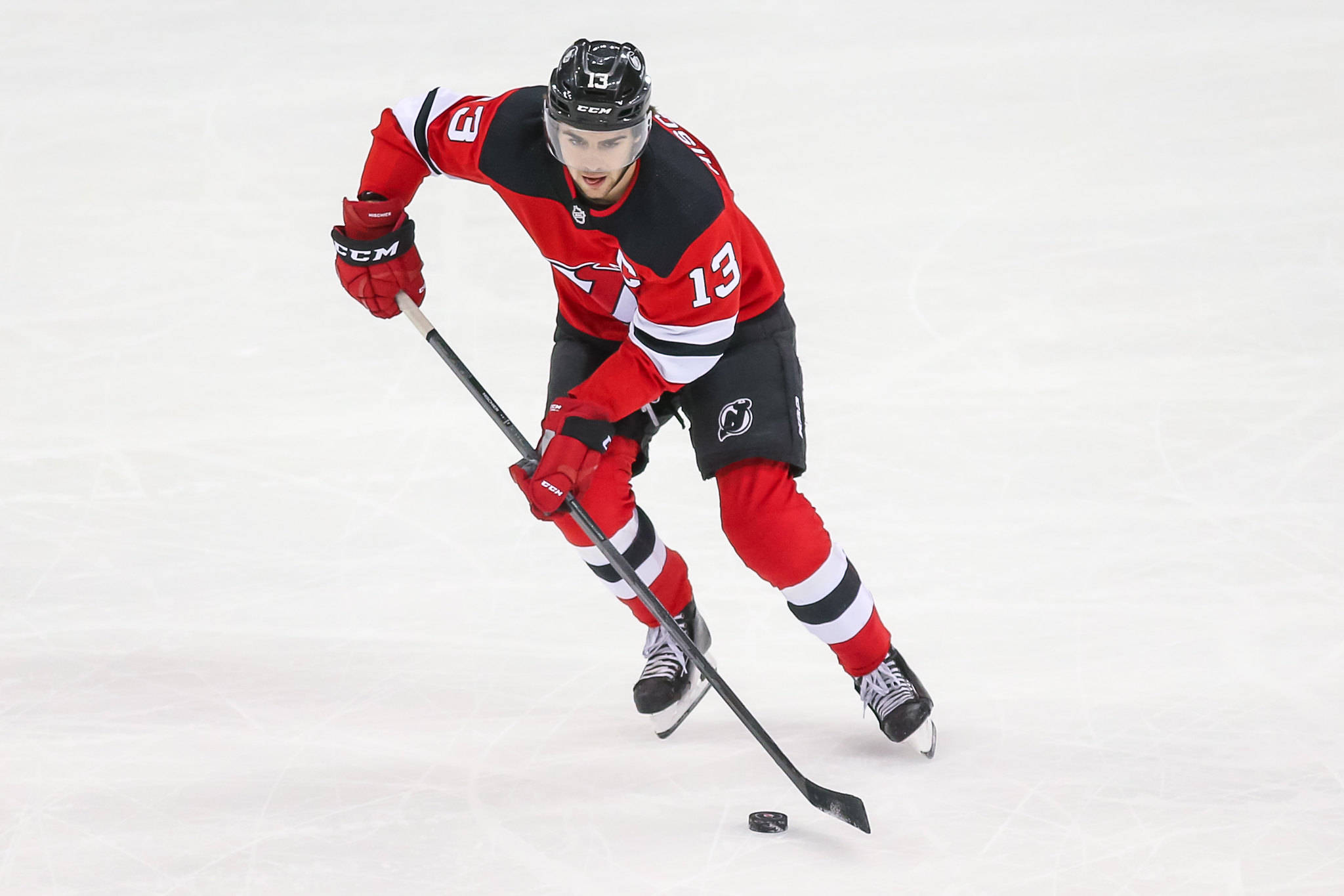 hockey 桌布 壁紙 — 一名身穿紅黑球衣的曲棍球運動員在冰場上向前傾斜，手持球桿滑行。