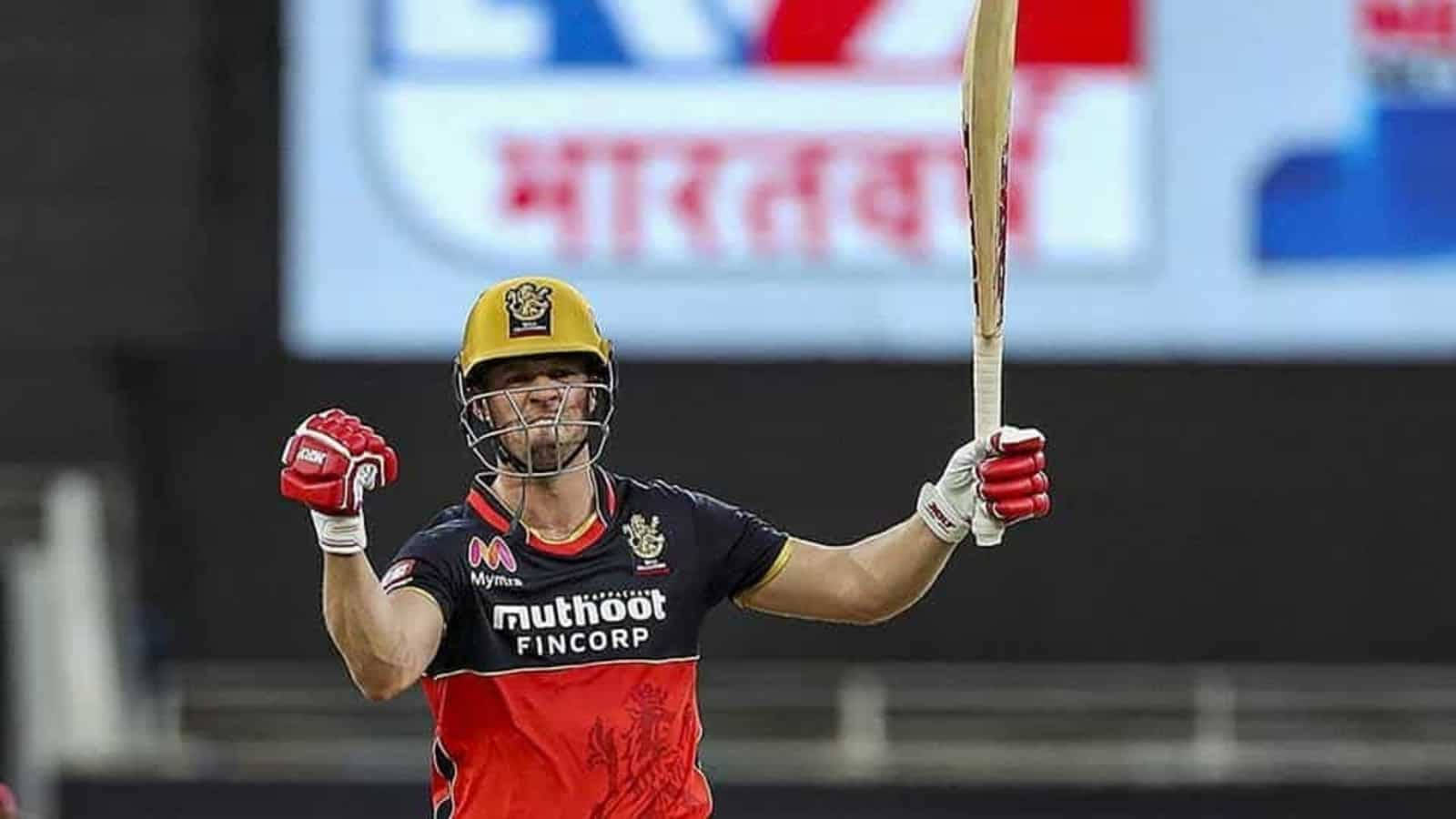Ab De Villiers 桌布 壁紙 — 一名身穿紅黑球衣的板球運動員在球場燈光下高舉球棒慶祝。