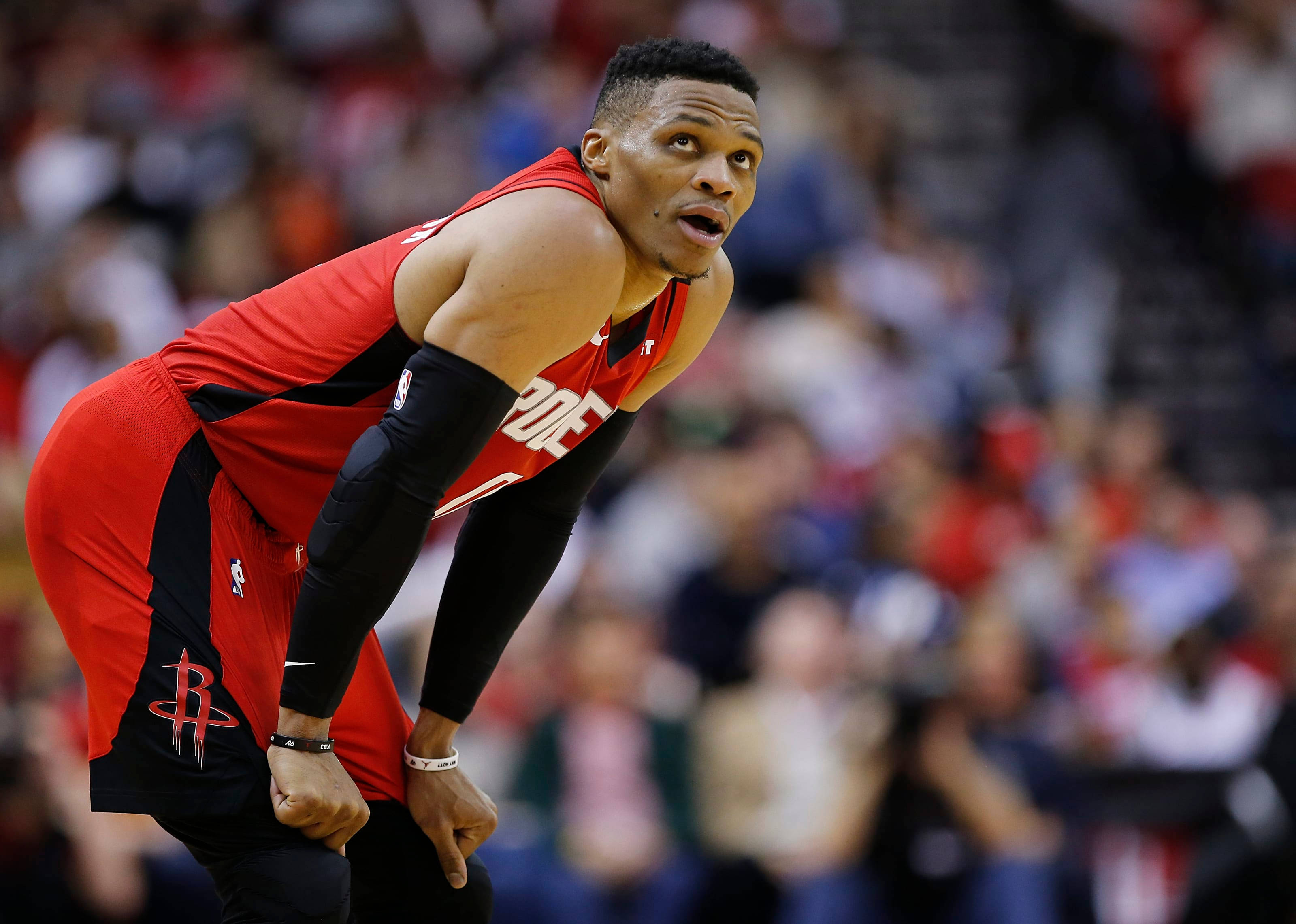 Westbrook 桌布 壁紙 — 一名身穿紅黑球衣的籃球運動員在比賽中向前傾身，背景是模糊的人群。