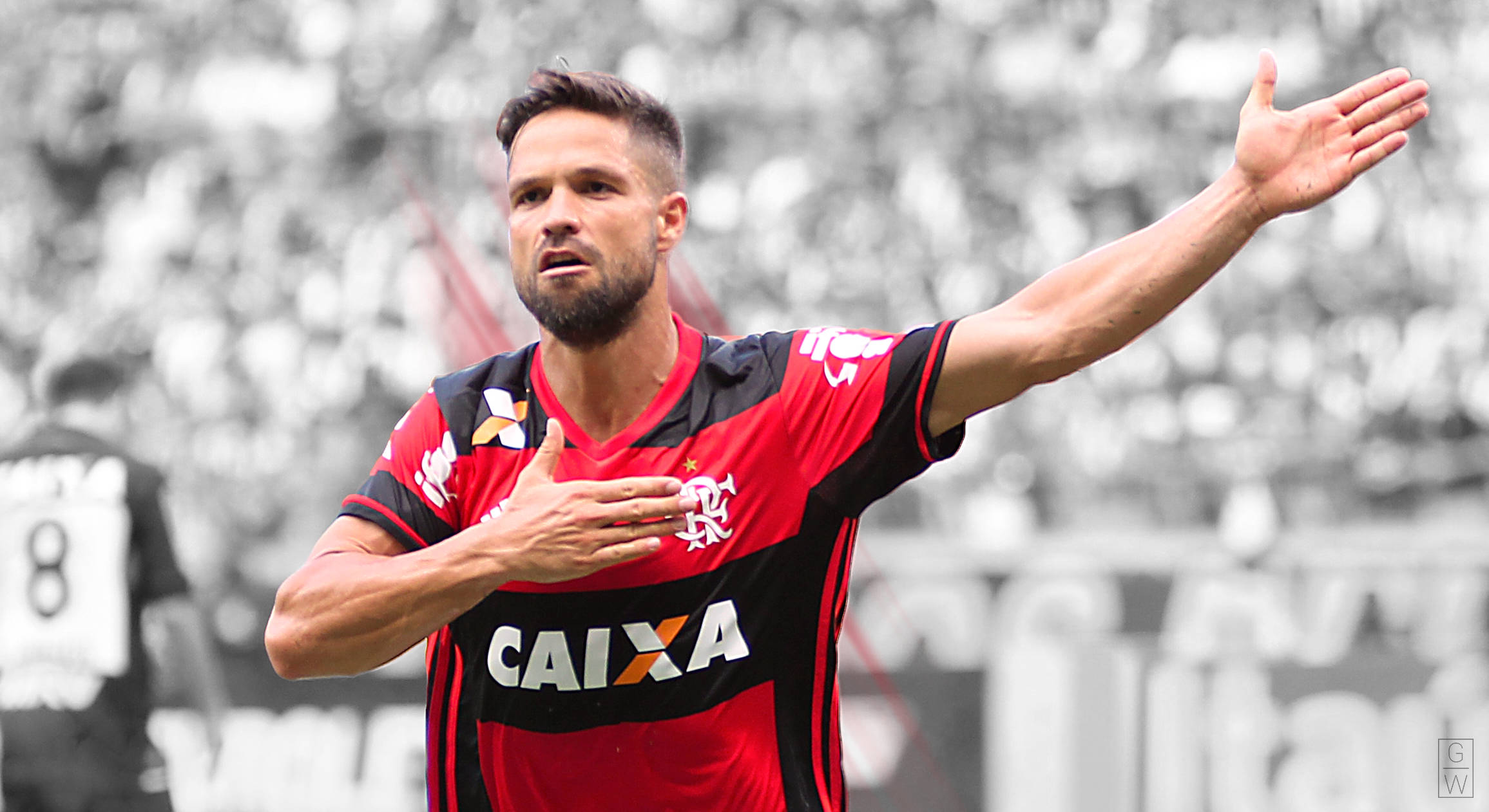 flamengo fc 桌布 壁紙 — 一名身穿紅黑球衣的足球員，一手放在胸前，另一隻手臂伸展，在模糊的體育場人群中慶祝。