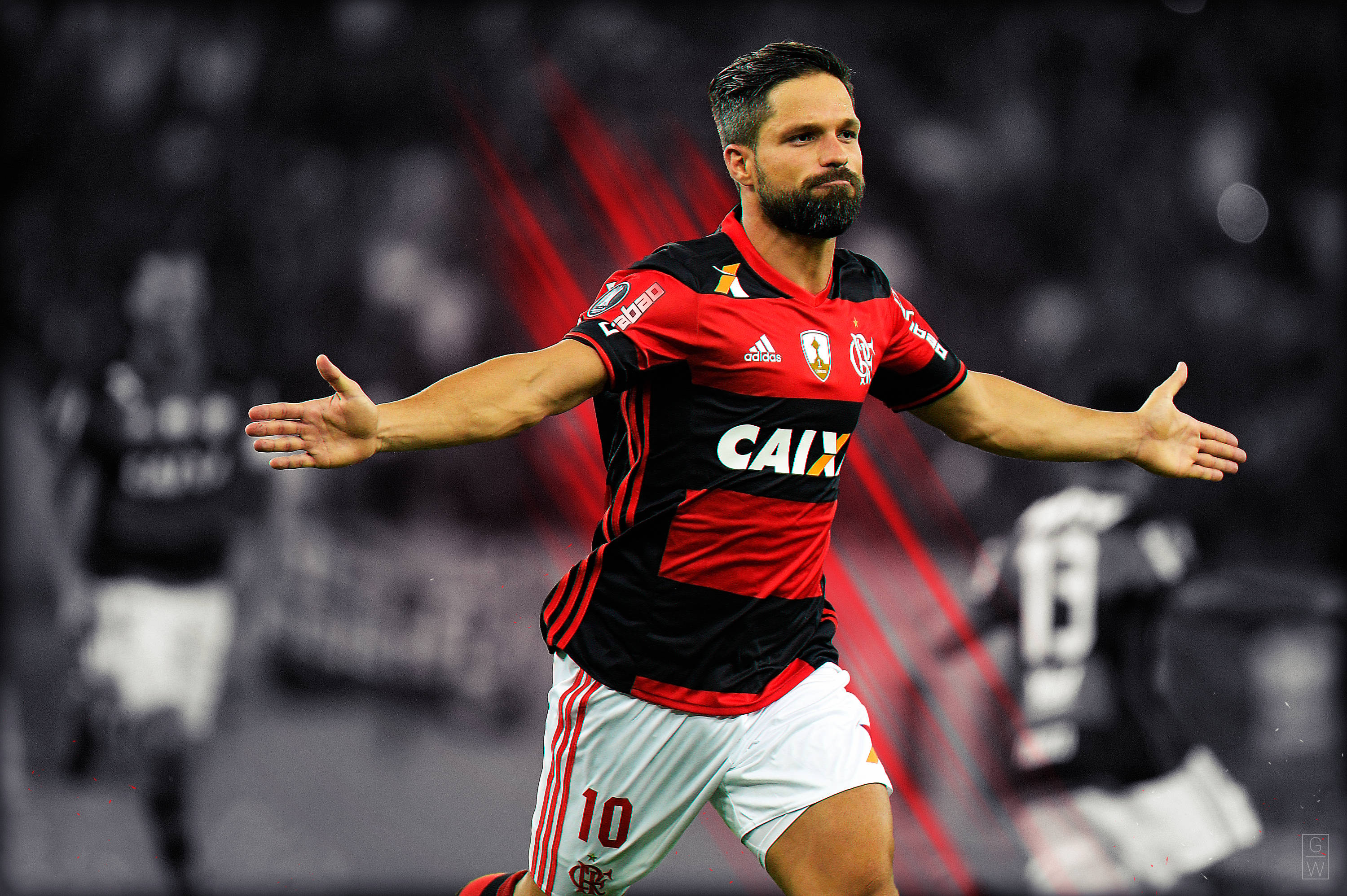flamengo fc 桌布 壁紙 — 一名身穿紅黑球衣的足球運動員在模糊的球場上張開雙臂慶祝。