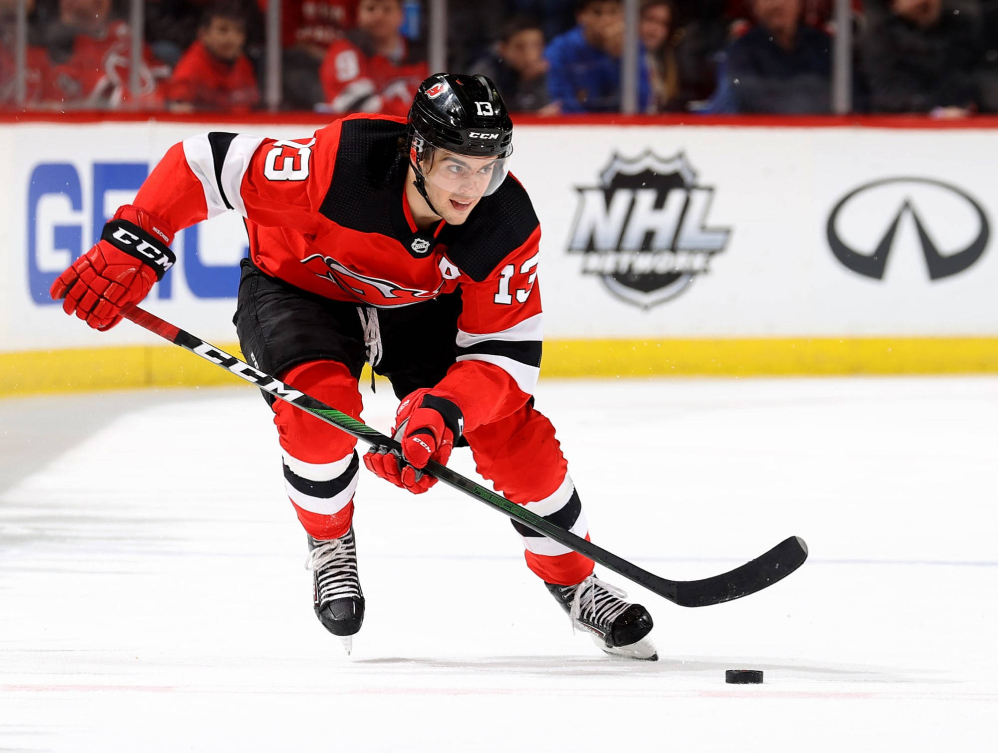 hockey 桌布 壁紙 — 一名身穿紅黑色球衣的冰球運動員在比賽中激烈地向前傾，在冰上持棍滑行。