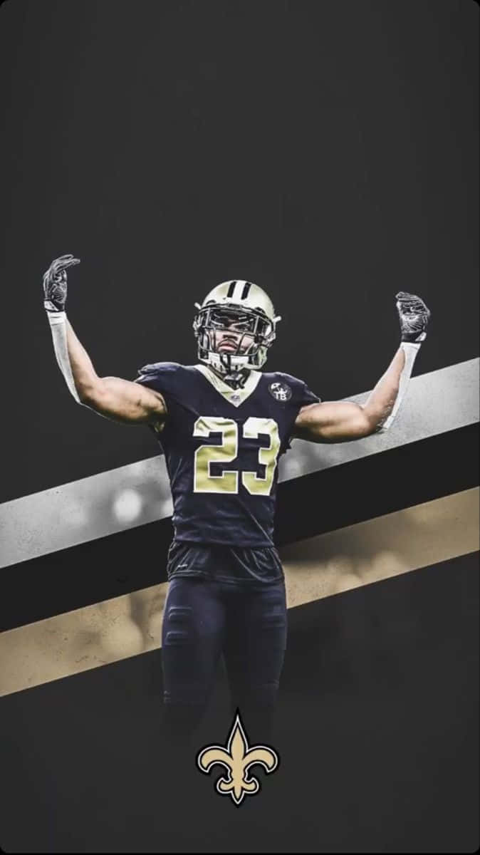 New Orleans Saints 桌布 壁紙 — 一名身穿紐奧良聖徒隊23號球衣的美式足球員，在帶有球隊條紋和標誌的深色背景前高舉雙臂慶祝。