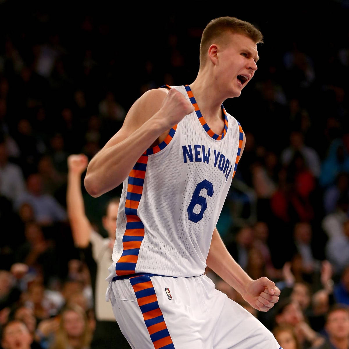 Kristaps Porzingis 桌布 壁紙 — 一名身穿紐約尼克隊球衣的籃球運動員在場館燈光下進行激烈比賽時握緊拳頭慶祝。