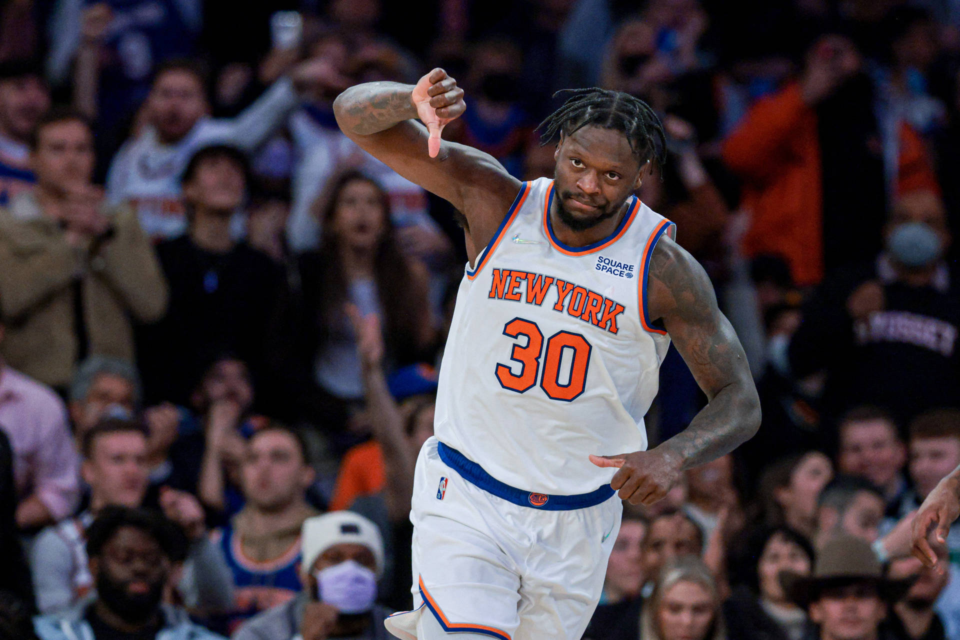 身穿紐約尼克隊球衣的籃球運動員向觀眾豎起拇指向下。 — NBA 壁紙
