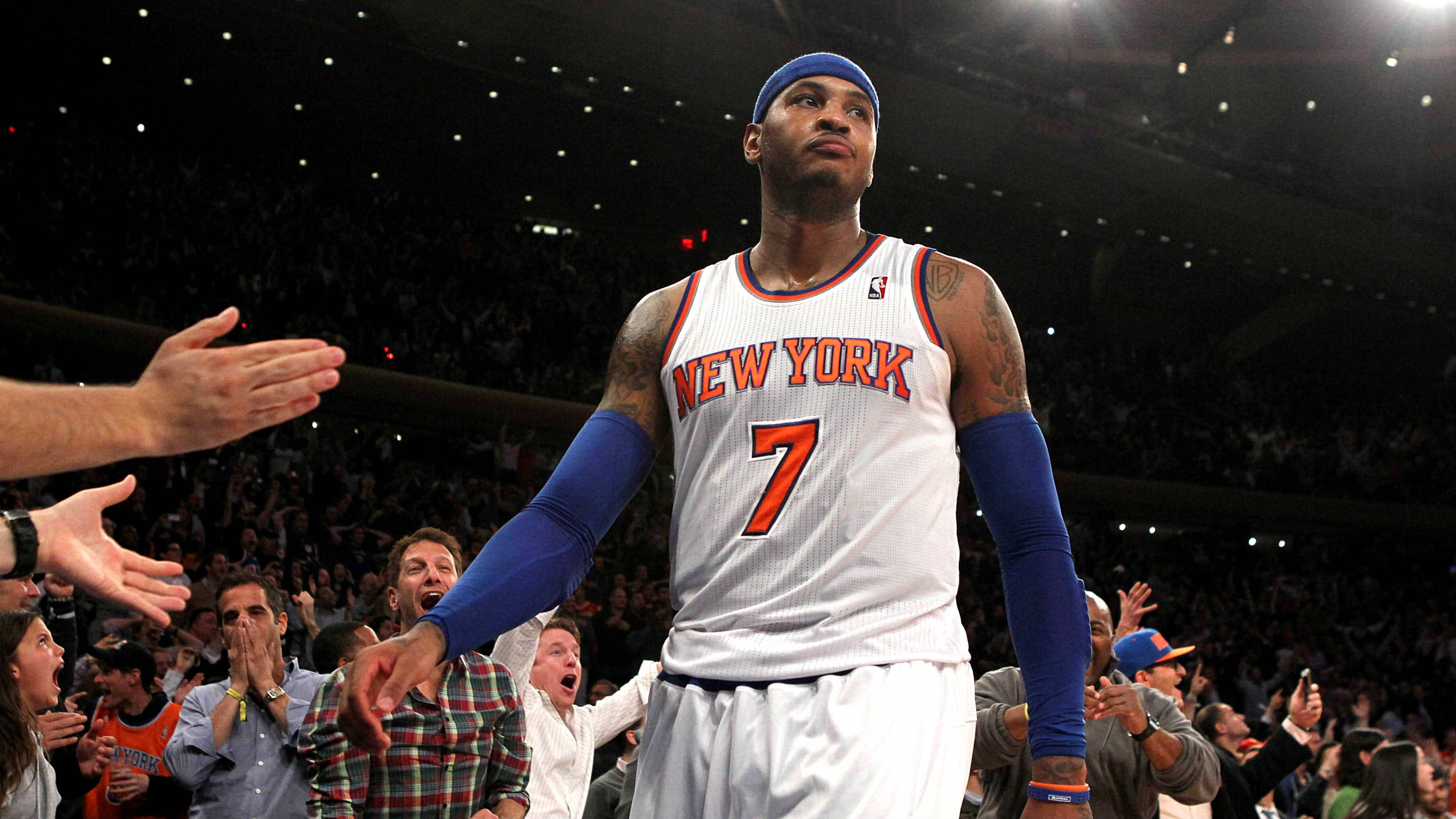Carmelo 桌布 壁紙 — 一名身穿紐約尼克隊球衣的籃球運動員站在球場中央，球迷在擠滿的場館中伸手觸碰他。