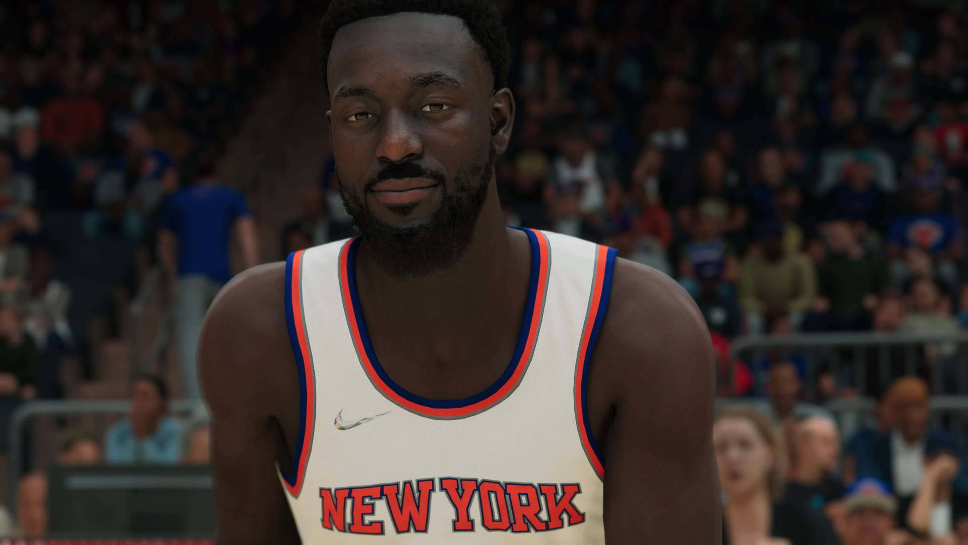 Kemba Walker 桌布 壁紙 — 一名身穿紐約尼克隊球衣的籃球運動員在擠滿觀眾的場館內專注地凝視著鏡頭。
