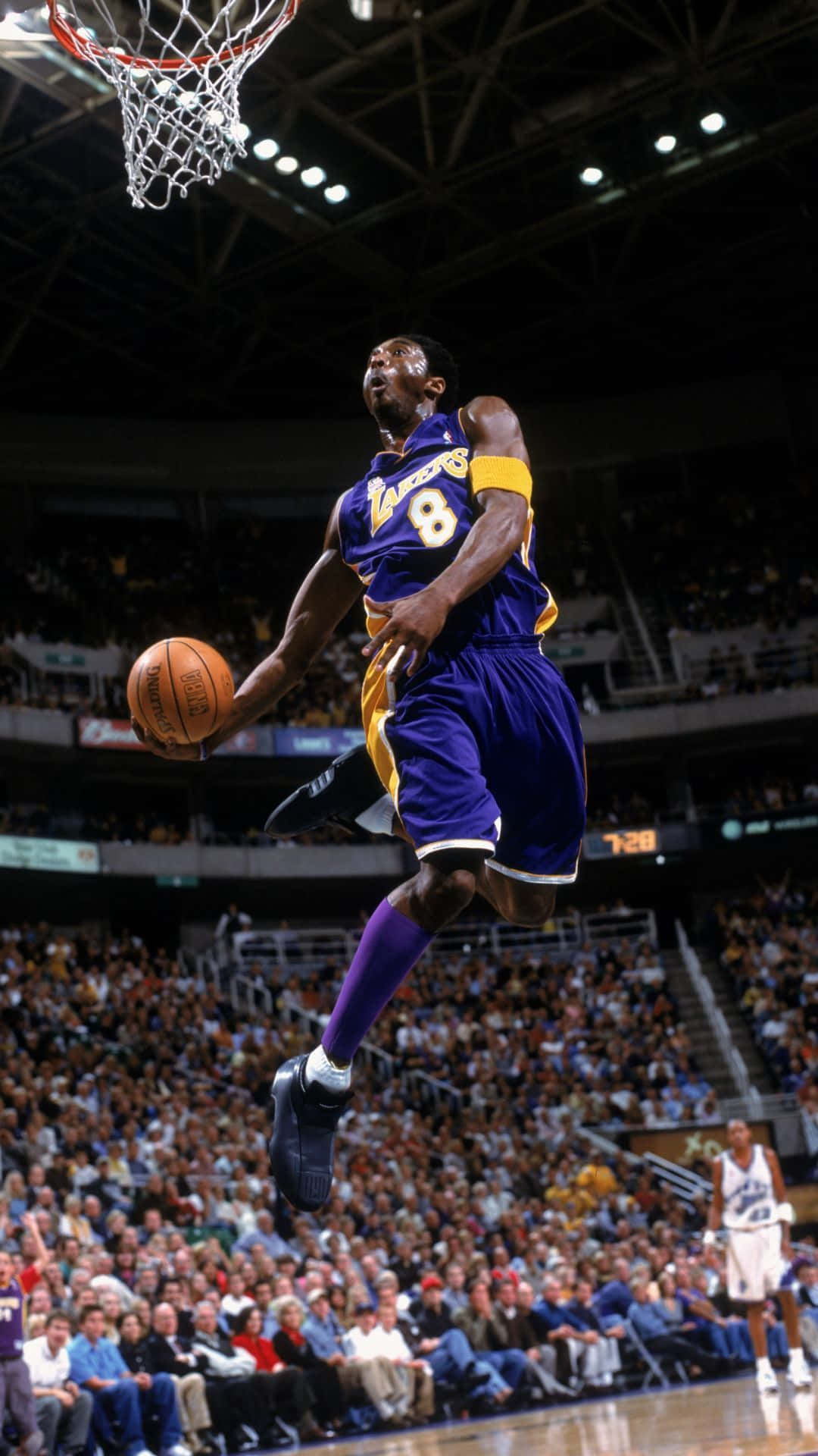 Aesthetic NBA 桌布 壁紙 — 一名身穿紫色湖人球衣的籃球運動員在明亮的燈光下，於擠滿觀眾的場館中空中灌籃。