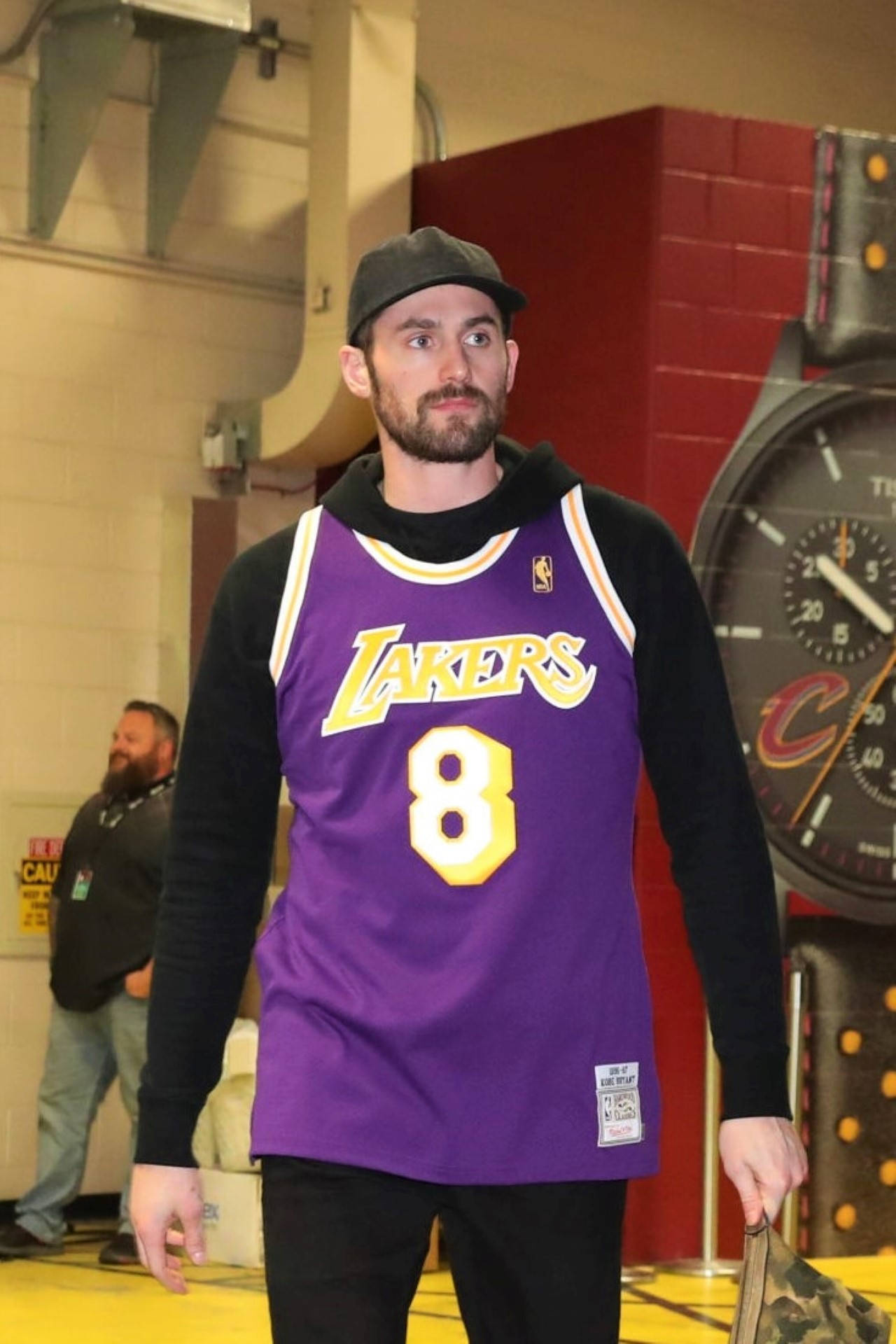 Kevin Love 桌布 壁紙 — 一名身穿紫色湖人隊8號球衣的男子站在體育館內，身後有一個大時鐘。