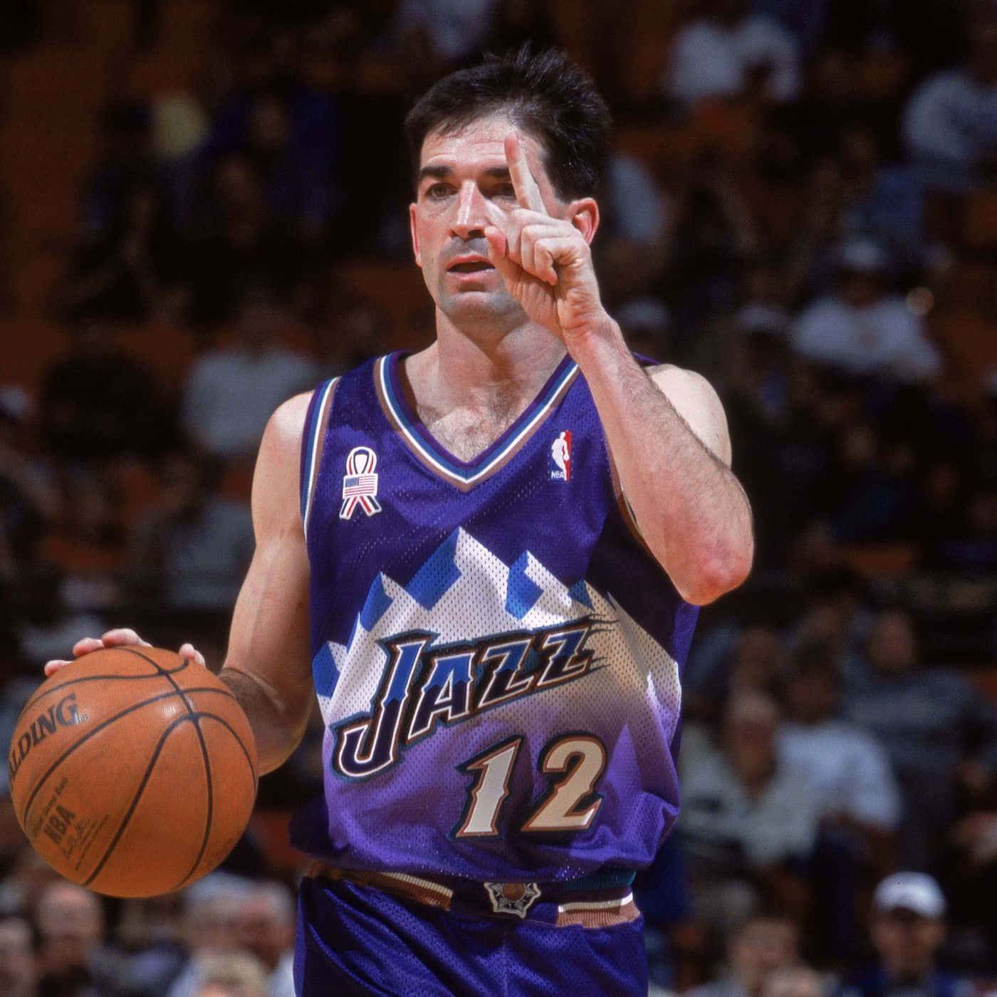 NBA 桌布 壁紙 — 一名身穿紫色爵士隊球衣的籃球運動員在比賽中持球並向上指，背景有觀眾。