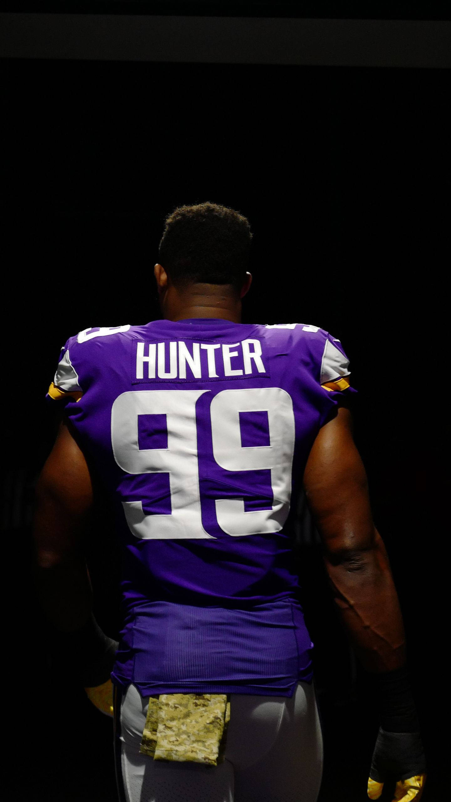 NFL Players 桌布 壁紙 — 一名身穿紫色球衣、印有名字 hunter 和號碼 99 的美式足球員背對鏡頭，站在黑色背景前。