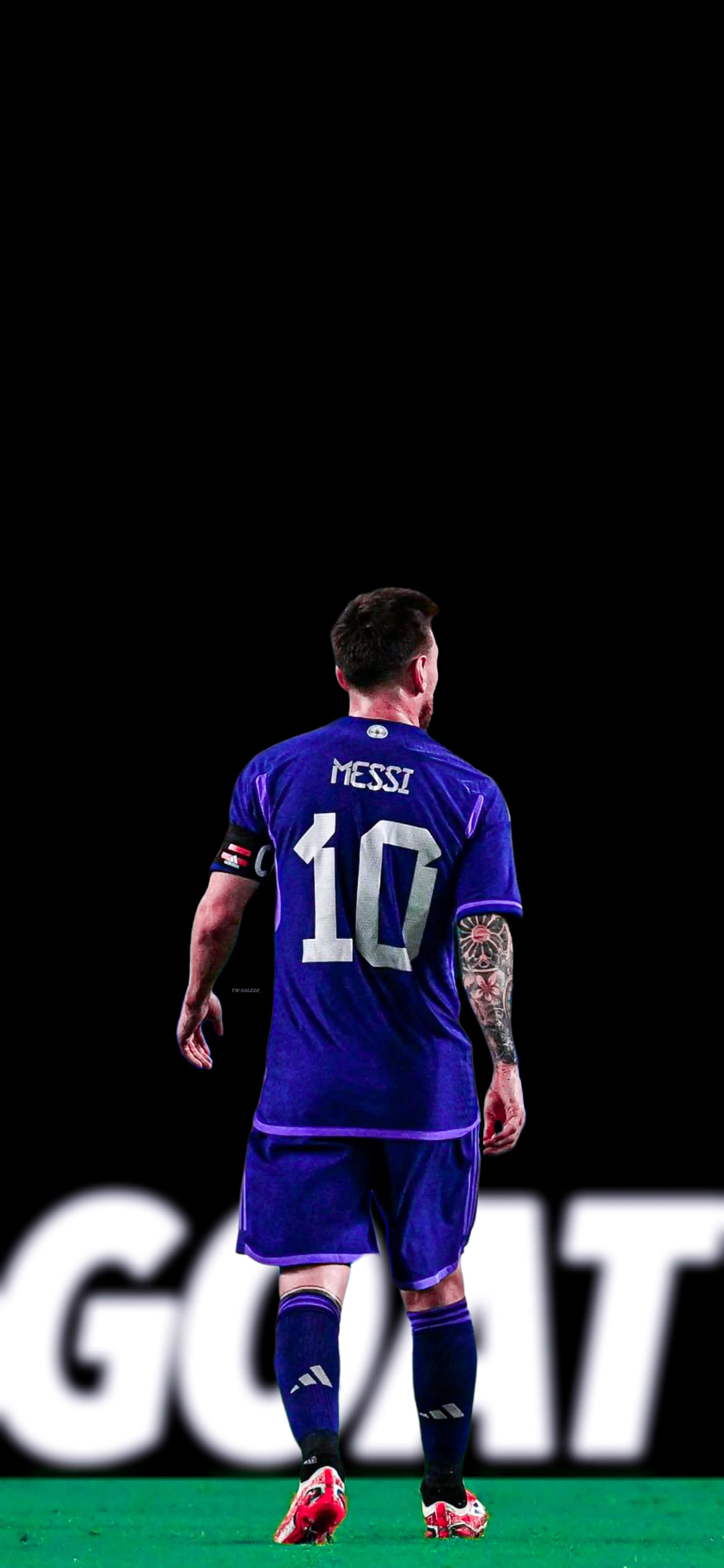 Messi Cool 桌布 壁紙 — 一名身穿紫色球衣、背號10的足球運動員在黑色背景前，帶著一個巨大的白色GOAT標誌，從綠色球場上走開。