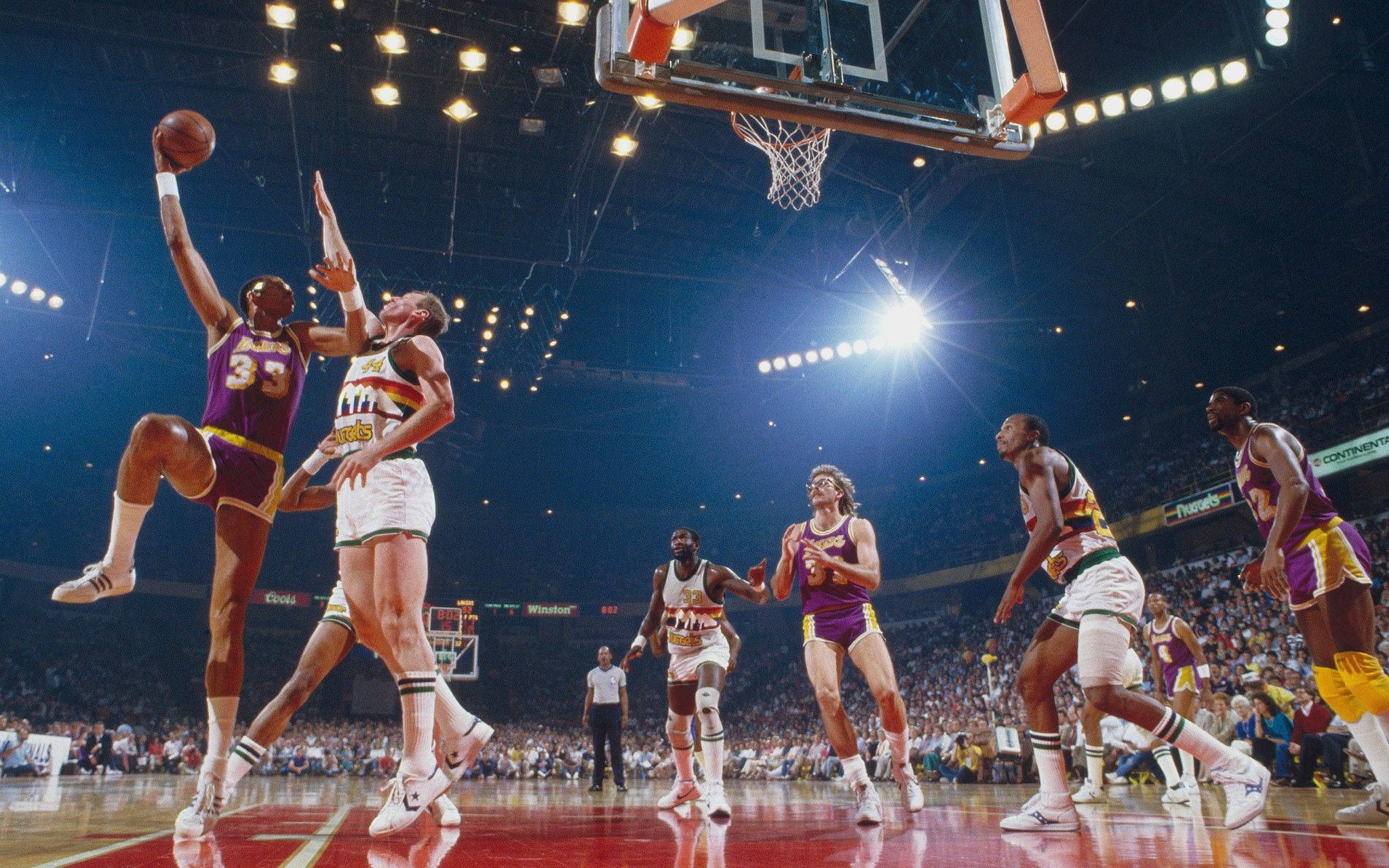 Kareem 桌布 壁紙 — 一名身穿紫色球衣的籃球運動員在場館燈光下跳向籃框，防守球員躍起封阻。