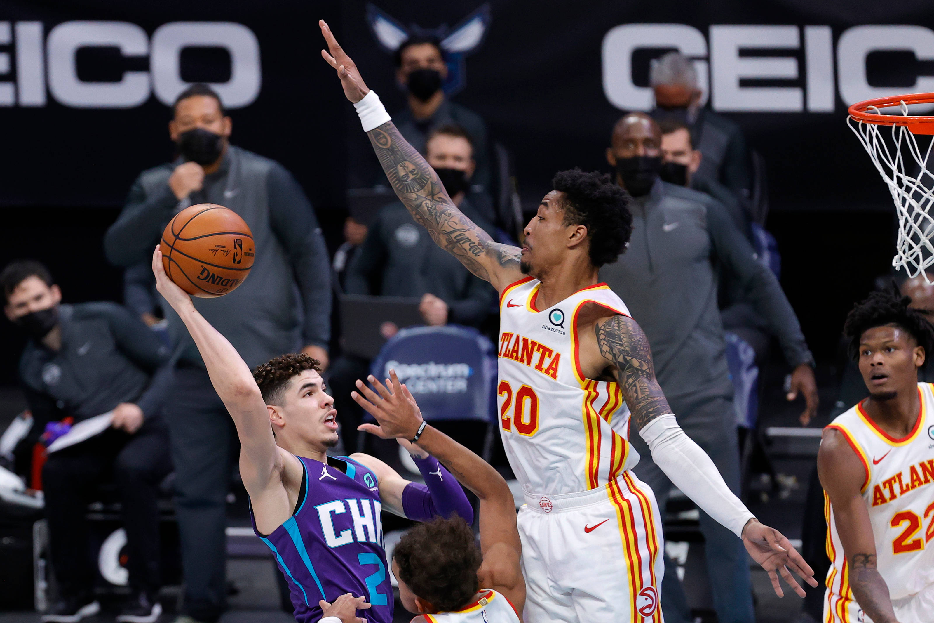 John Collins 桌布 壁紙 — 一名身穿紫色球衣的籃球運動員正在投籃，同時被一名身穿白色球衣、紋身可見的亞特蘭大老鷹隊球員防守。