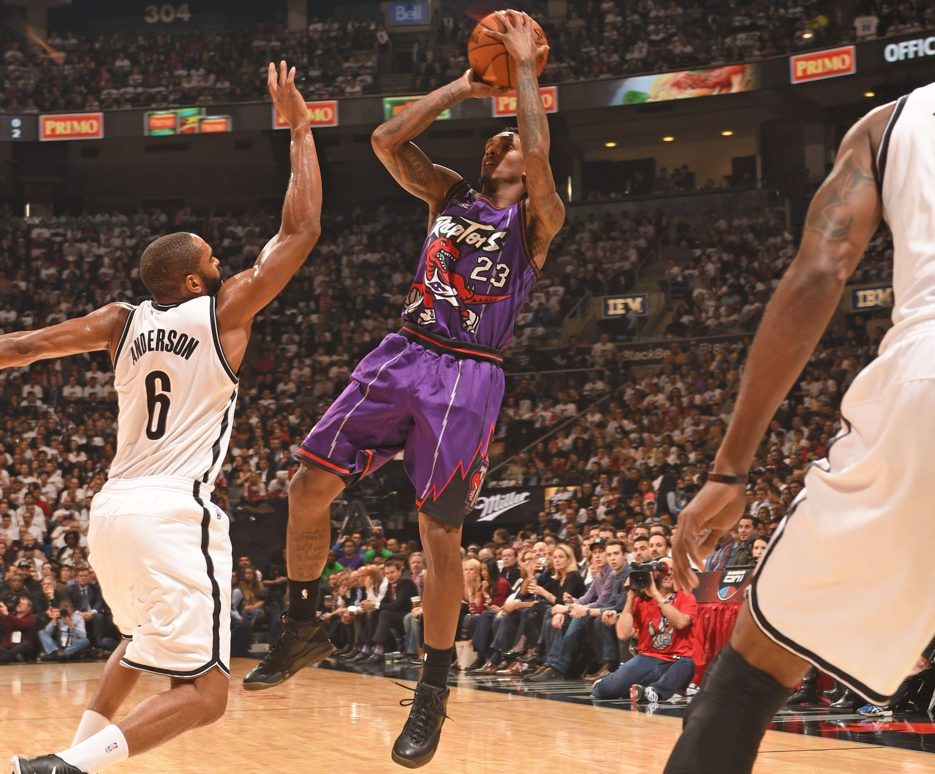 Lou Williams 桌布 壁紙 — 一名身穿紫色的多倫多暴龍球員跳起投籃，而身穿白色的布魯克林籃網防守球員在擠滿觀眾的場館比賽中試圖封阻他。