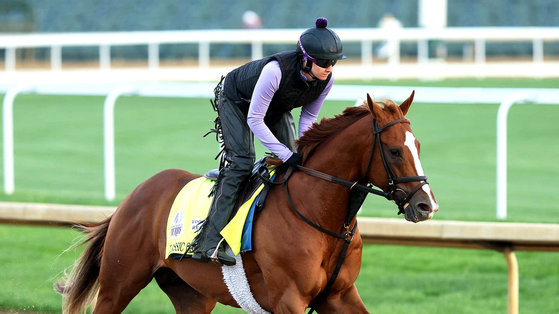 Kentucky Derby 桌布 壁紙 — 一名身穿紫色裝備的騎師俯身騎著一匹帶有白色星紋的栗色賽馬，在綠色草地賽道上奔馳。