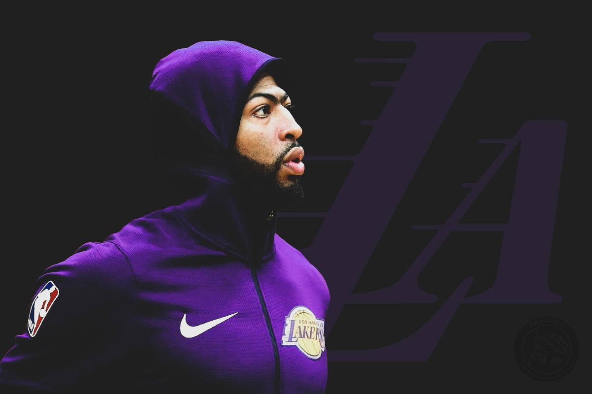 Anthony Davis 桌布 壁紙 — 一名身穿紫色連帽衫的籃球運動員在帶有大型LA標誌的深色背景下凝視著。