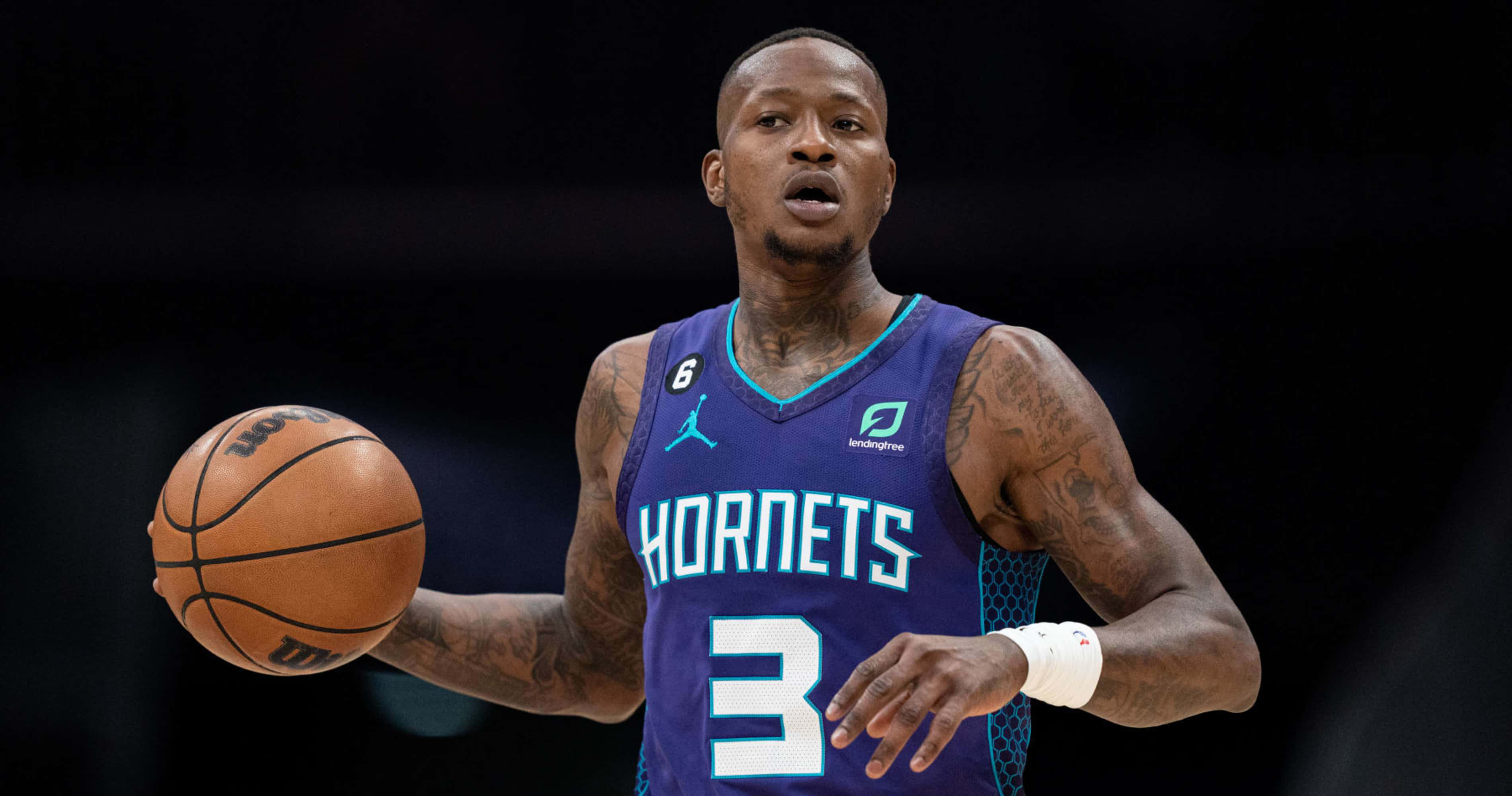 NBA 桌布 壁紙 — 一名身穿紫色黃蜂隊球衣的籃球運動員在場館燈光下比賽中持球。