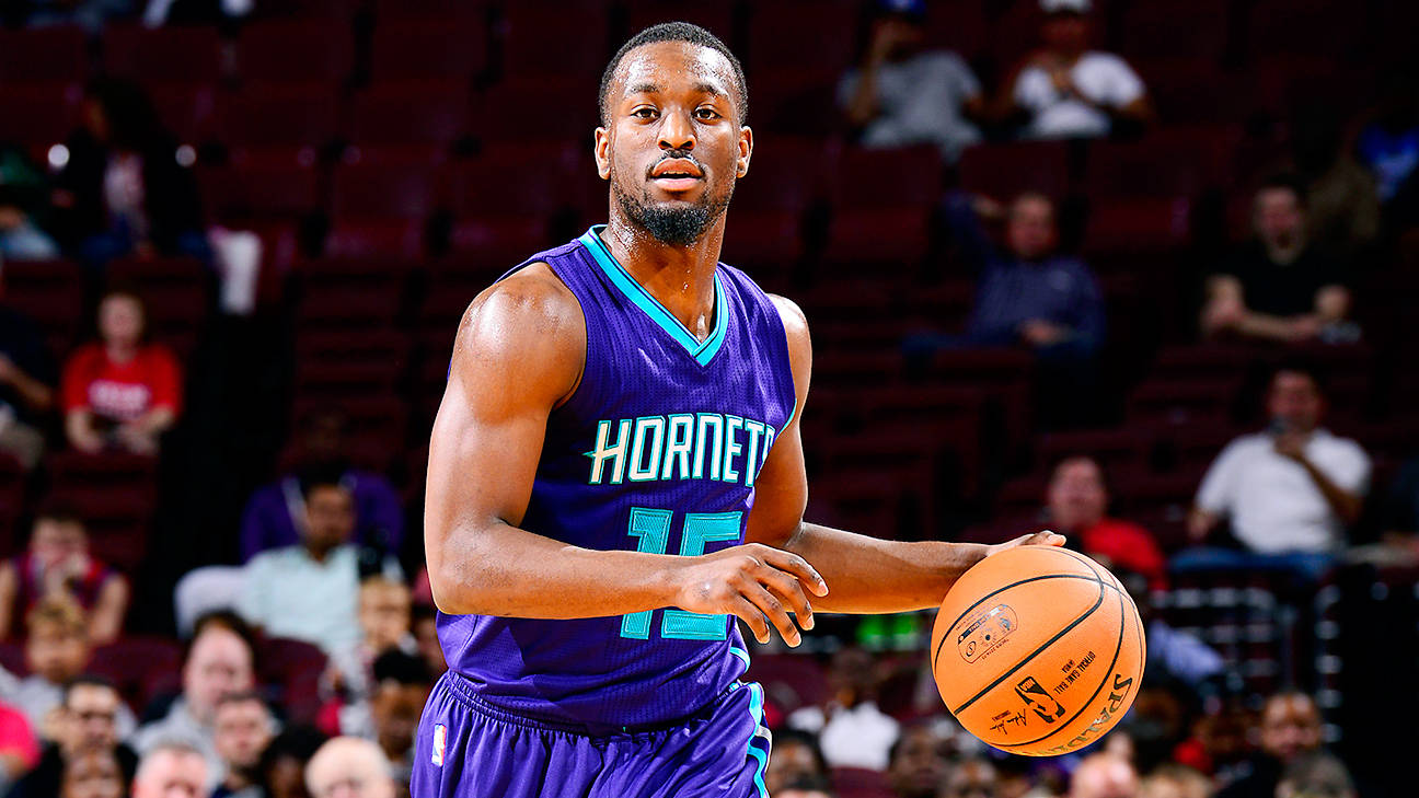 Kemba Walker 桌布 壁紙 — 一名身穿紫色黃蜂隊球衣的籃球運動員在場館燈光下運著橙色籃球，背景是紅色座位上的模糊觀眾。