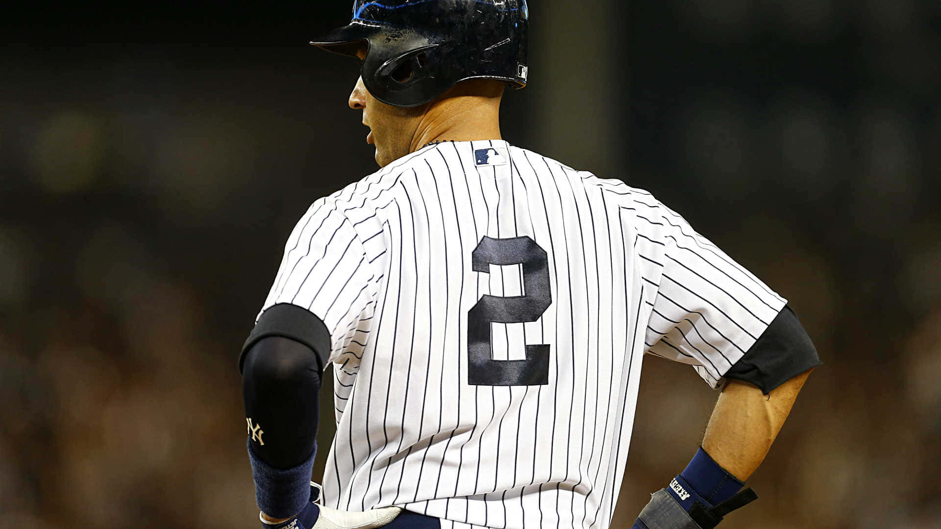 Derek Jeter 桌布 壁紙 — 一名身穿細條紋制服、背號二號的棒球運動員在夜間球場燈光下背對鏡頭。
