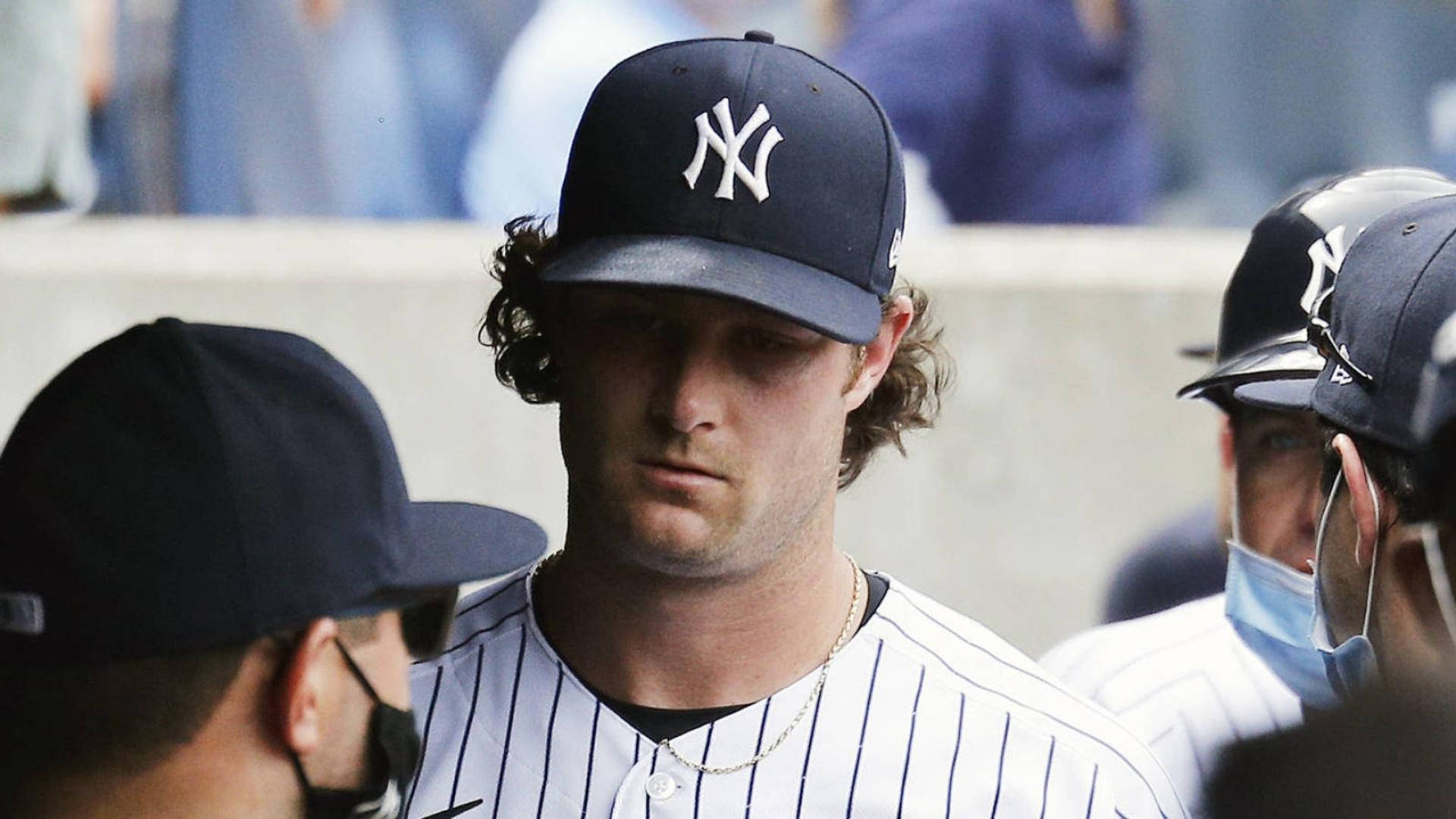 Gerrit Cole 桌布 壁紙 — 一名身穿細條紋制服和帽子的紐約洋基棒球運動員在休息區低頭，表情嚴肅。