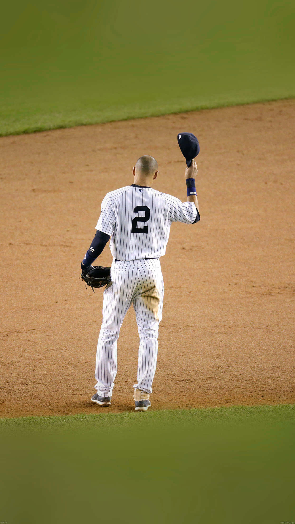 Derek Jeter 桌布 壁紙 — 一名身穿細條紋球衣、背號2號的棒球選手站在被綠草包圍的泥土內野中揮動帽子。