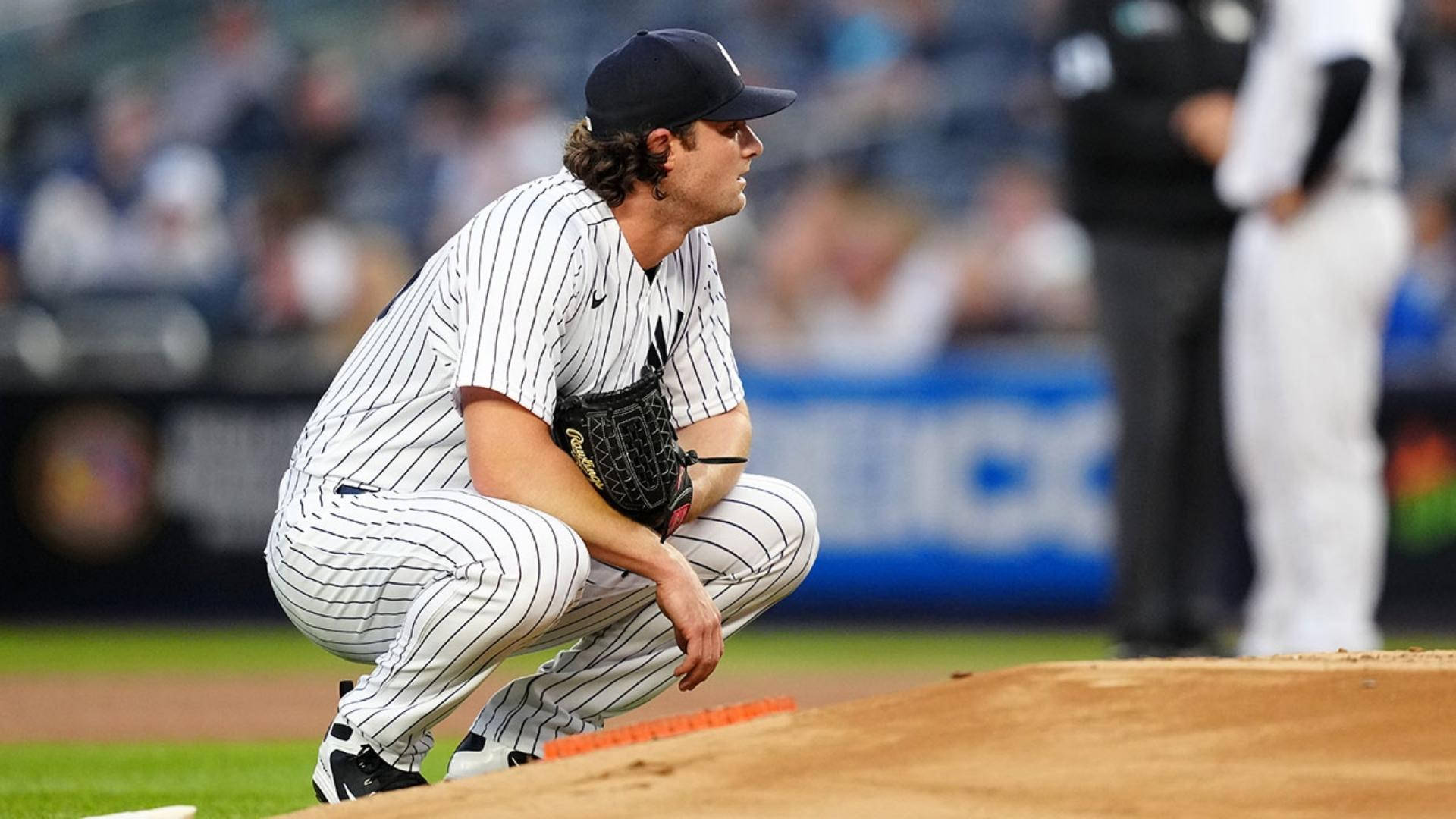 Gerrit Cole 桌布 壁紙 — 一名身穿細條紋球衣的棒球投手在夜間比賽期間，蹲在球場燈光下的投手丘上。