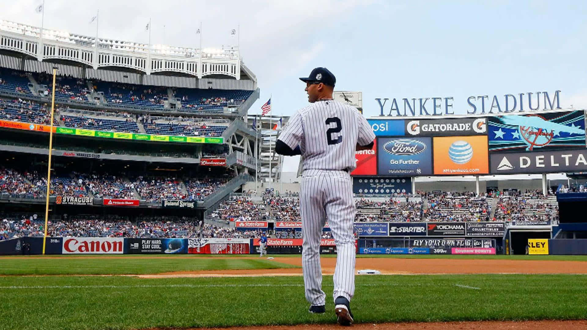 Derek Jeter 桌布 壁紙 — 一名身穿細條紋球衣的棒球運動員在晴朗的天空下走過洋基球場的場地。