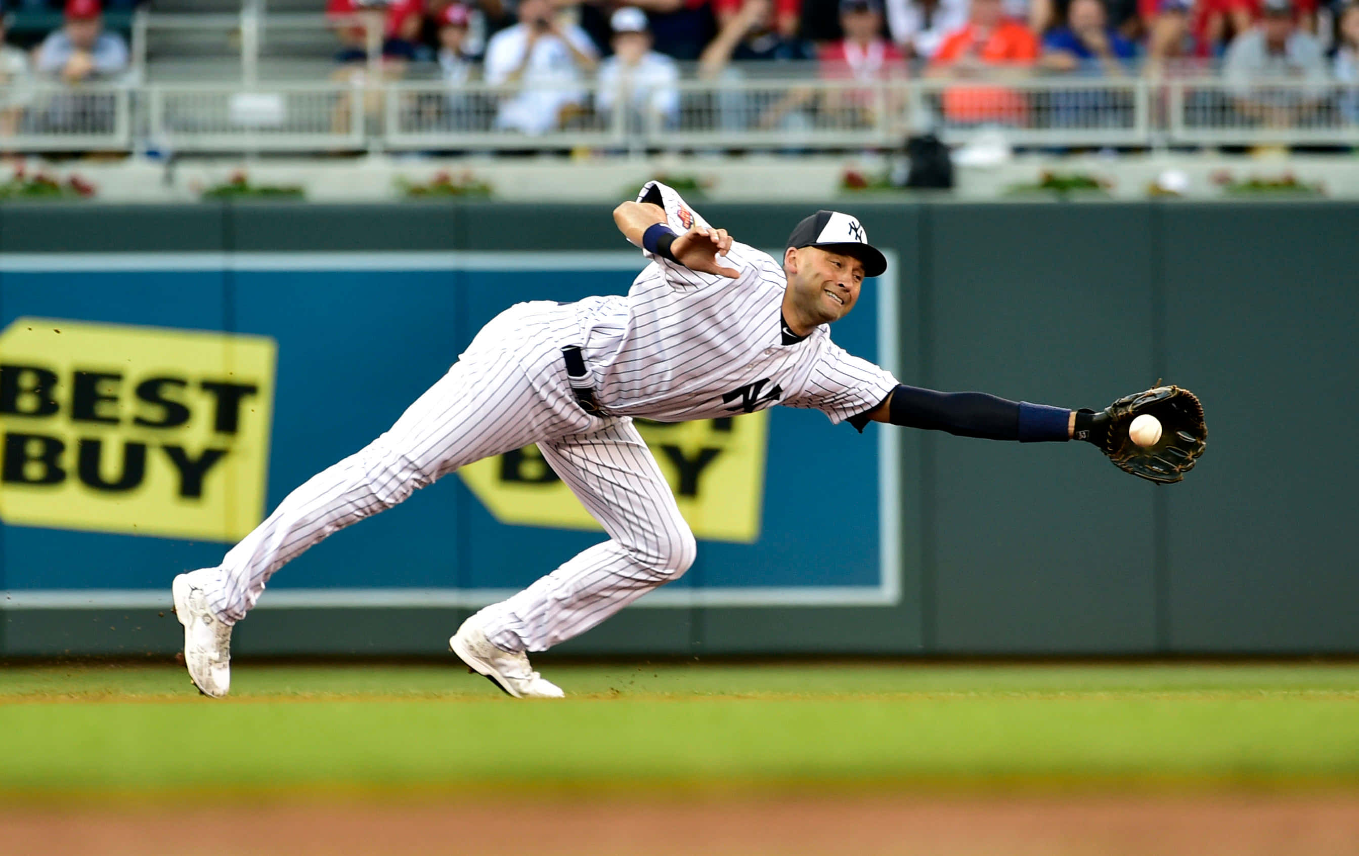 Derek Jeter 桌布 壁紙 — 一名身穿細條紋球衣的棒球選手在比賽中向前飛撲，試圖用手套接住球。