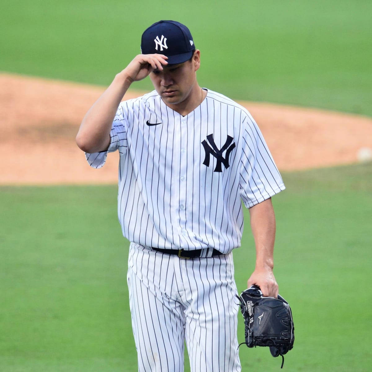 masahiro tanaka 桌布 壁紙 — 一名身穿細條紋球衣的紐約洋基棒球選手，手按額頭，神情沮喪地離開球場。