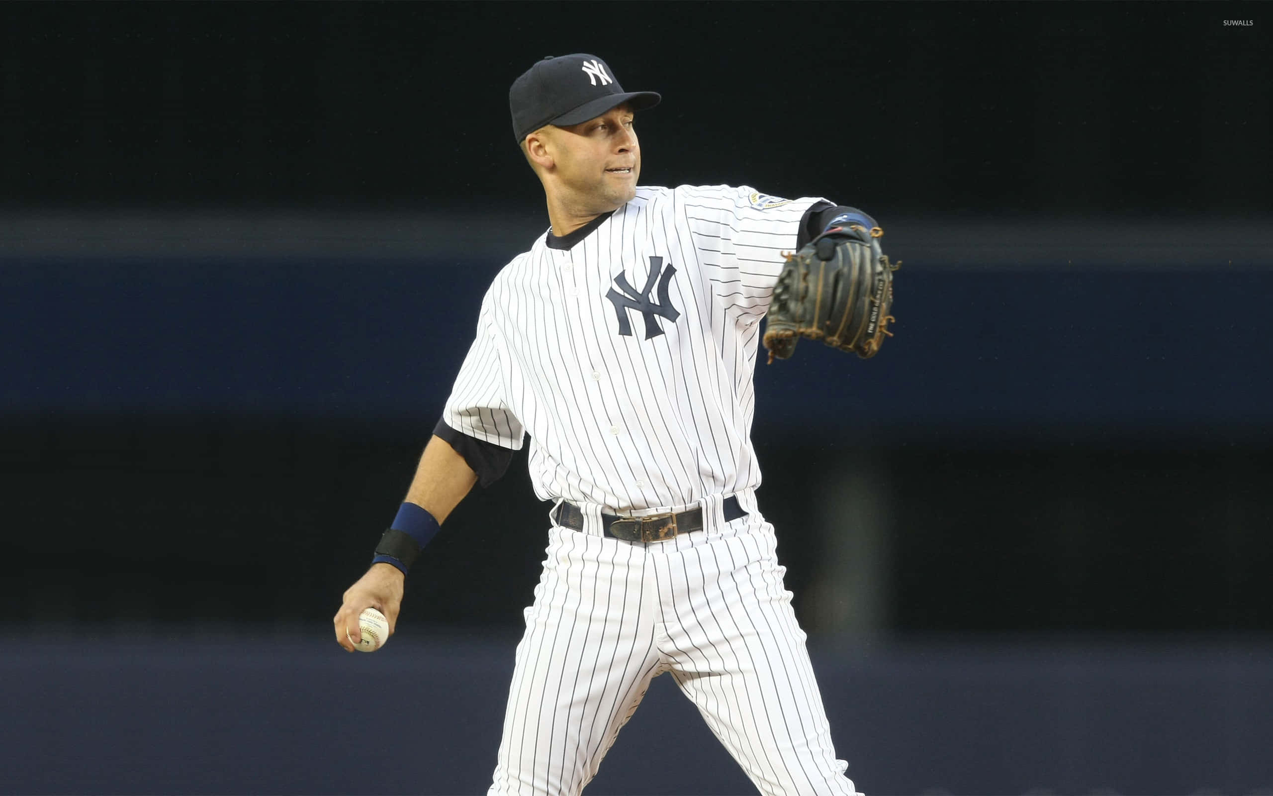 Yankees Logo 桌布 壁紙 — 一名身穿細條紋球衣的紐約洋基棒球選手，在夜間比賽中準備投擲棒球。