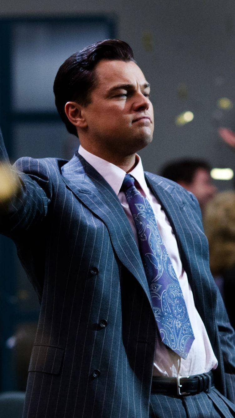 Wolf Of Wall Street 桌布 壁紙 — 一名身穿細條紋西裝和佩斯利領帶的男子，在昏暗的房間裡帶著勝利的表情拋灑五彩紙屑。