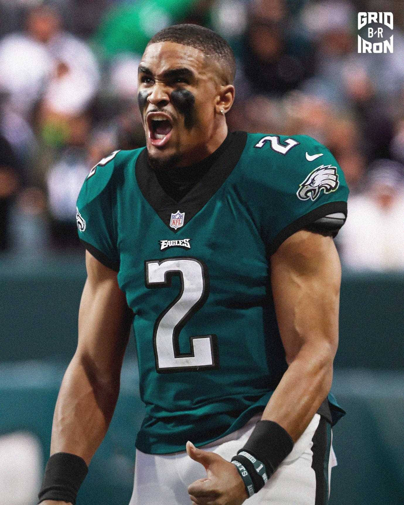 Jalen Hurts Eagles 桌布 壁紙 — 一名身穿綠色二號球衣的費城老鷹隊美式足球員在體育場燈光下比賽時激烈咆哮。