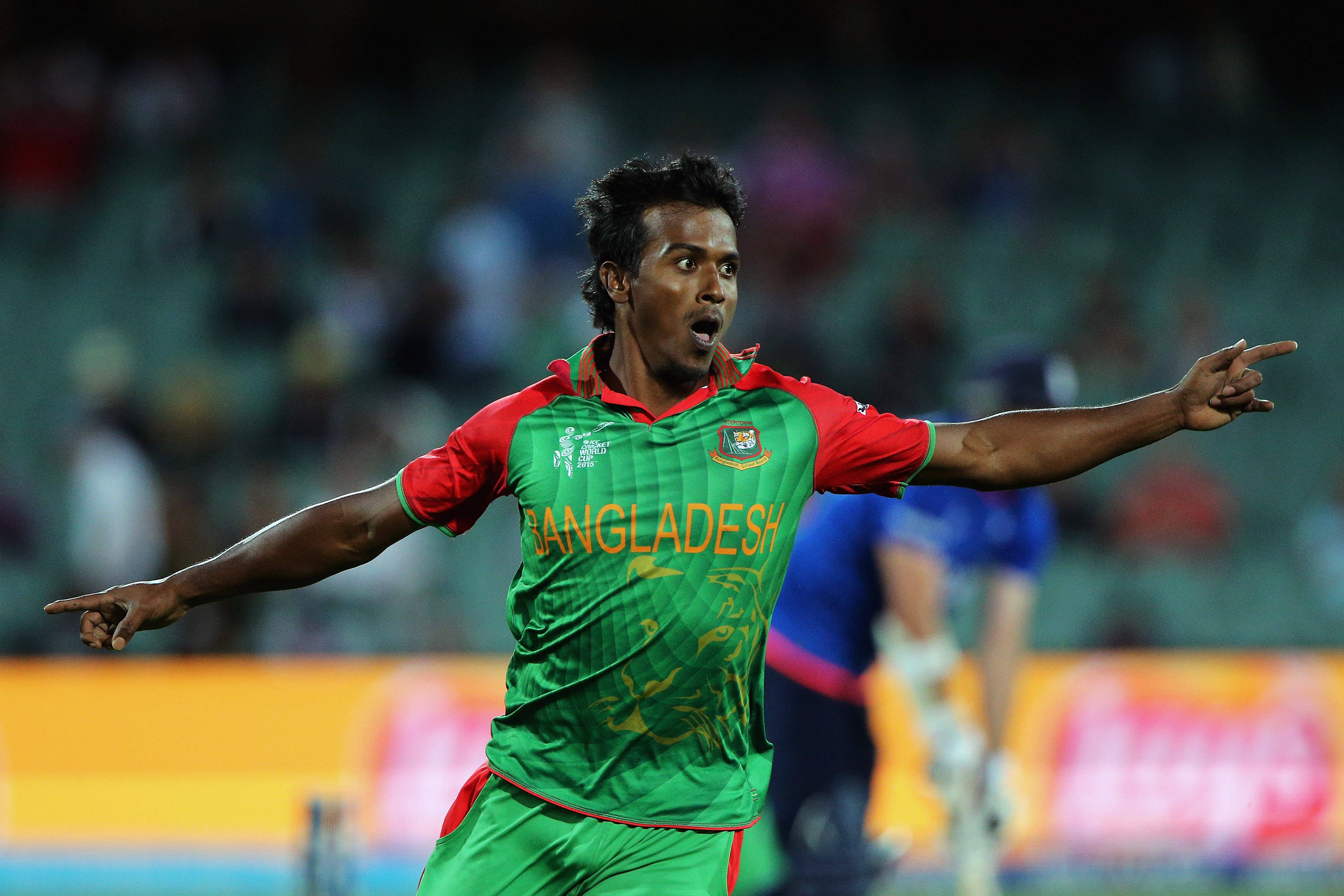 Bangladesh Cricket 桌布 壁紙 — 一名身穿綠色和紅色球衣的孟加拉板球運動員在球場燈光下張開雙臂慶祝。