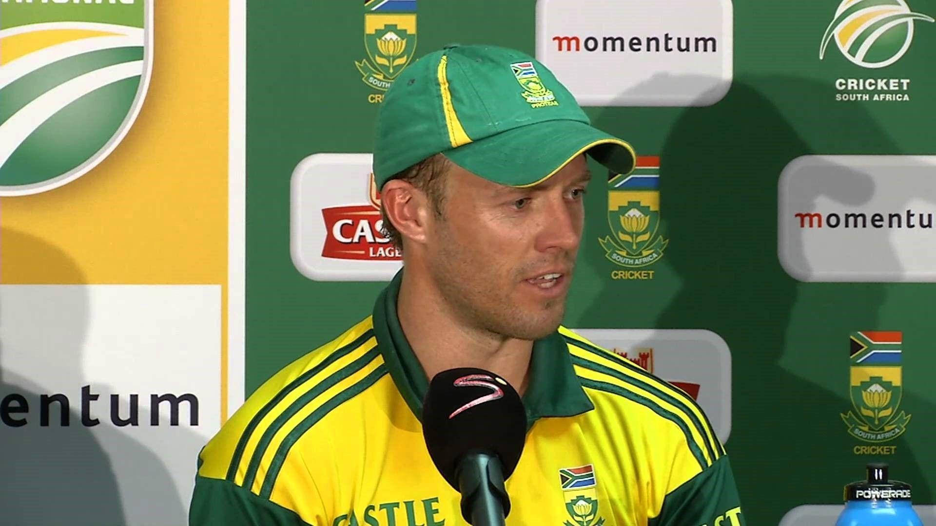 Ab De Villiers 桌布 壁紙 — 一名身穿綠色和黃色球衣的南非板球運動員在記者會上對著麥克風發言。