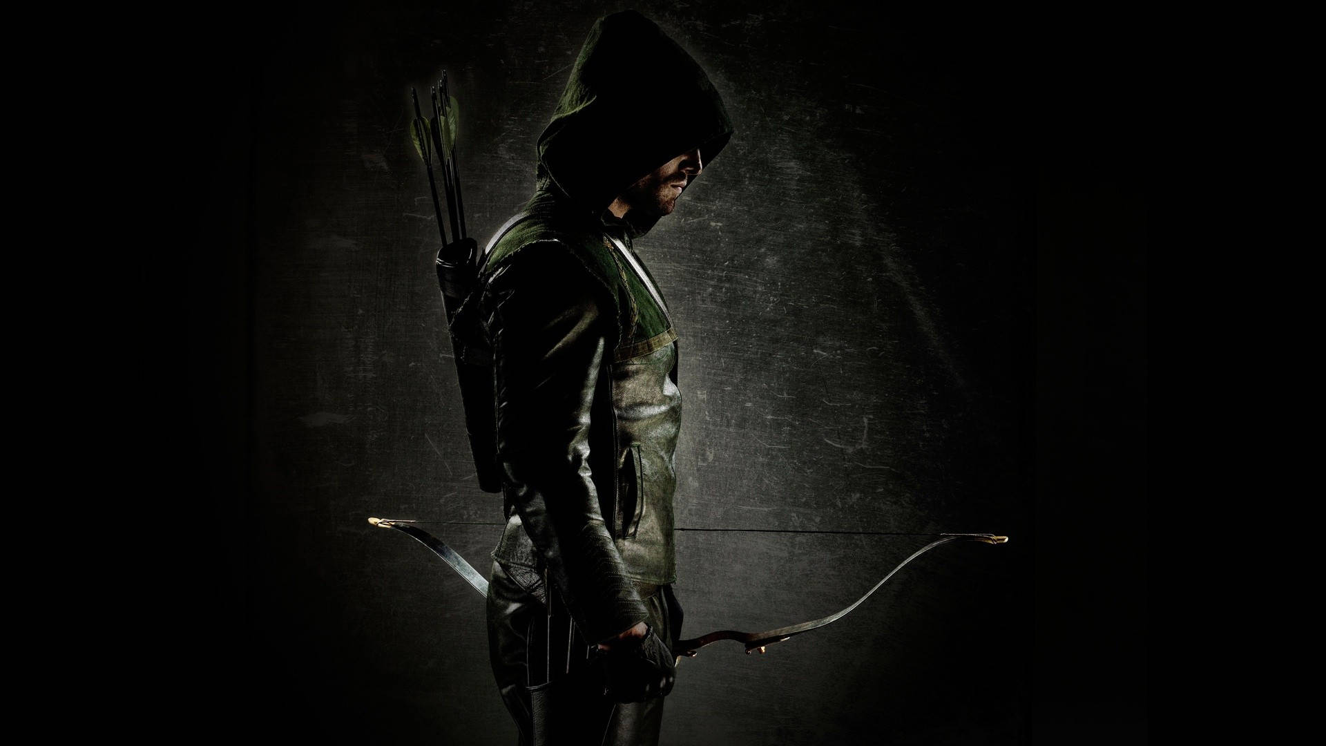 Green Arrow 桌布 壁紙 — 一名身穿綠色和黑色盔甲的兜帽弓箭手站在陰影中，手持弓，背上背著箭。