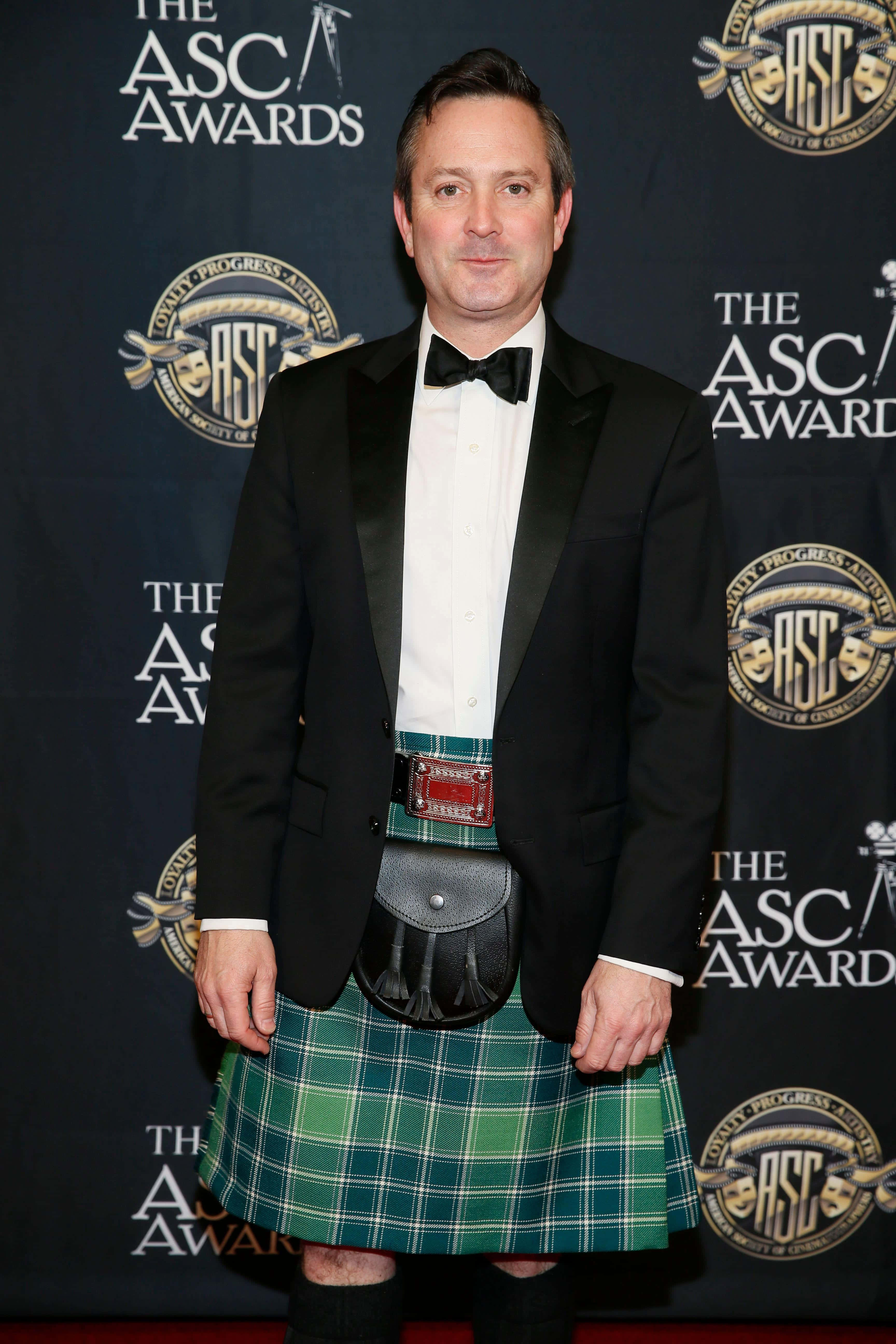 thomas lennon 桌布 壁紙 — 一名身穿綠色格紋蘇格蘭裙和黑色禮服的男士自信地站在ASC頒獎典禮的紅地毯上。